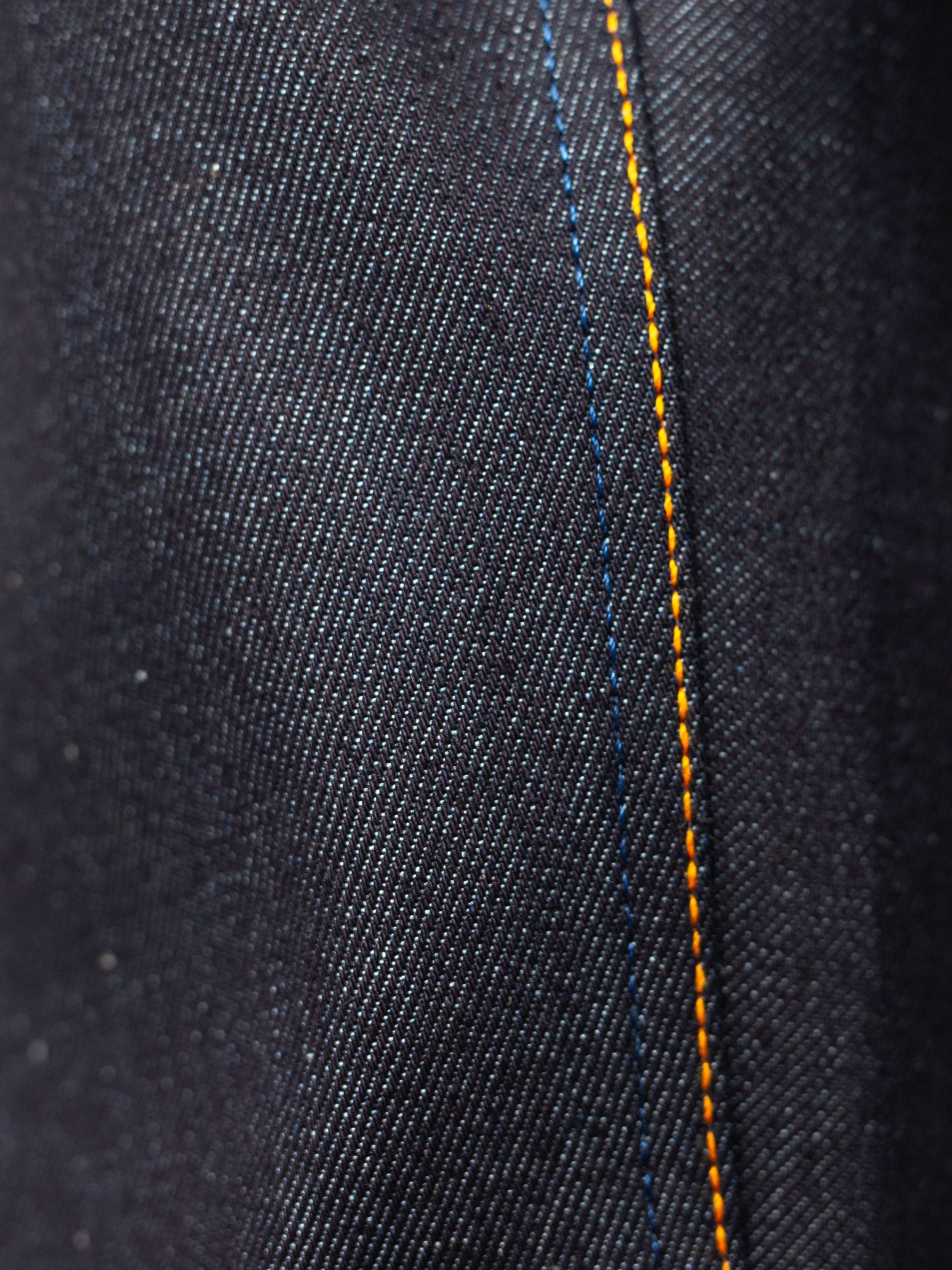 Nudie Jeans Lean Dean Dry Japan Selvage, showing a close-up of the redcast selvedge denim texture and orange seam stitching.
