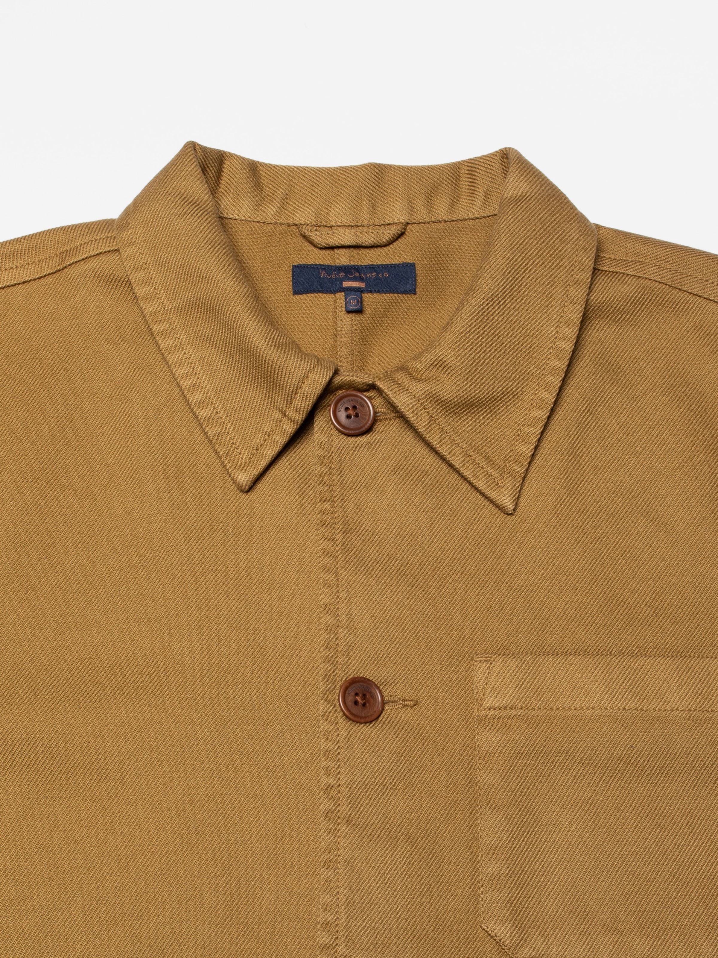 Nudie Jeans Barney Worker Jacket in Brown Olive, Nahaufnahme von Kragen, Knöpfen und Twill-Baumwollgewebe.