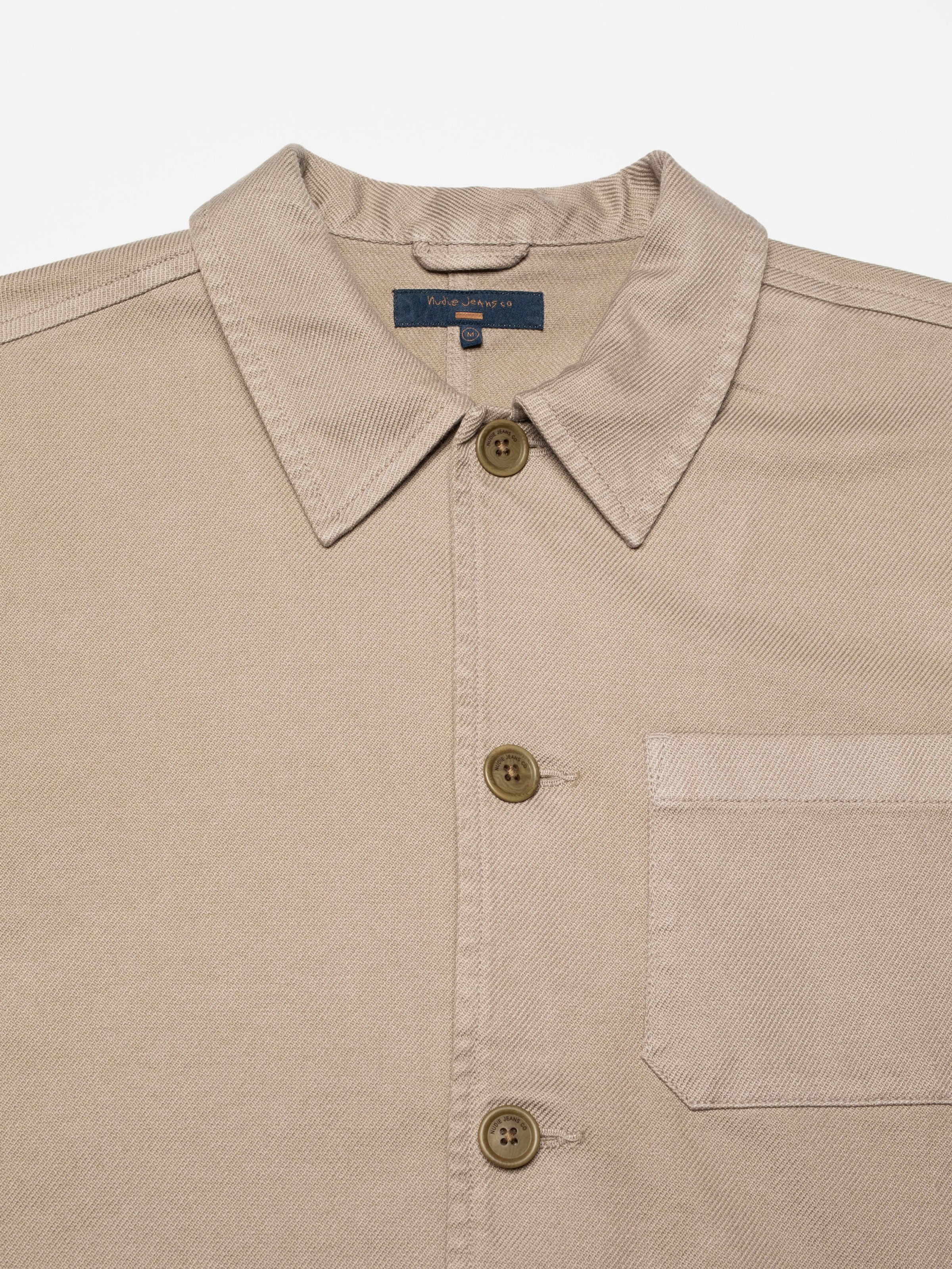 Nudie Jeans Barney Worker Jacket in Mud, close-up of the upper front showing the point collar, buttons and twill texture.