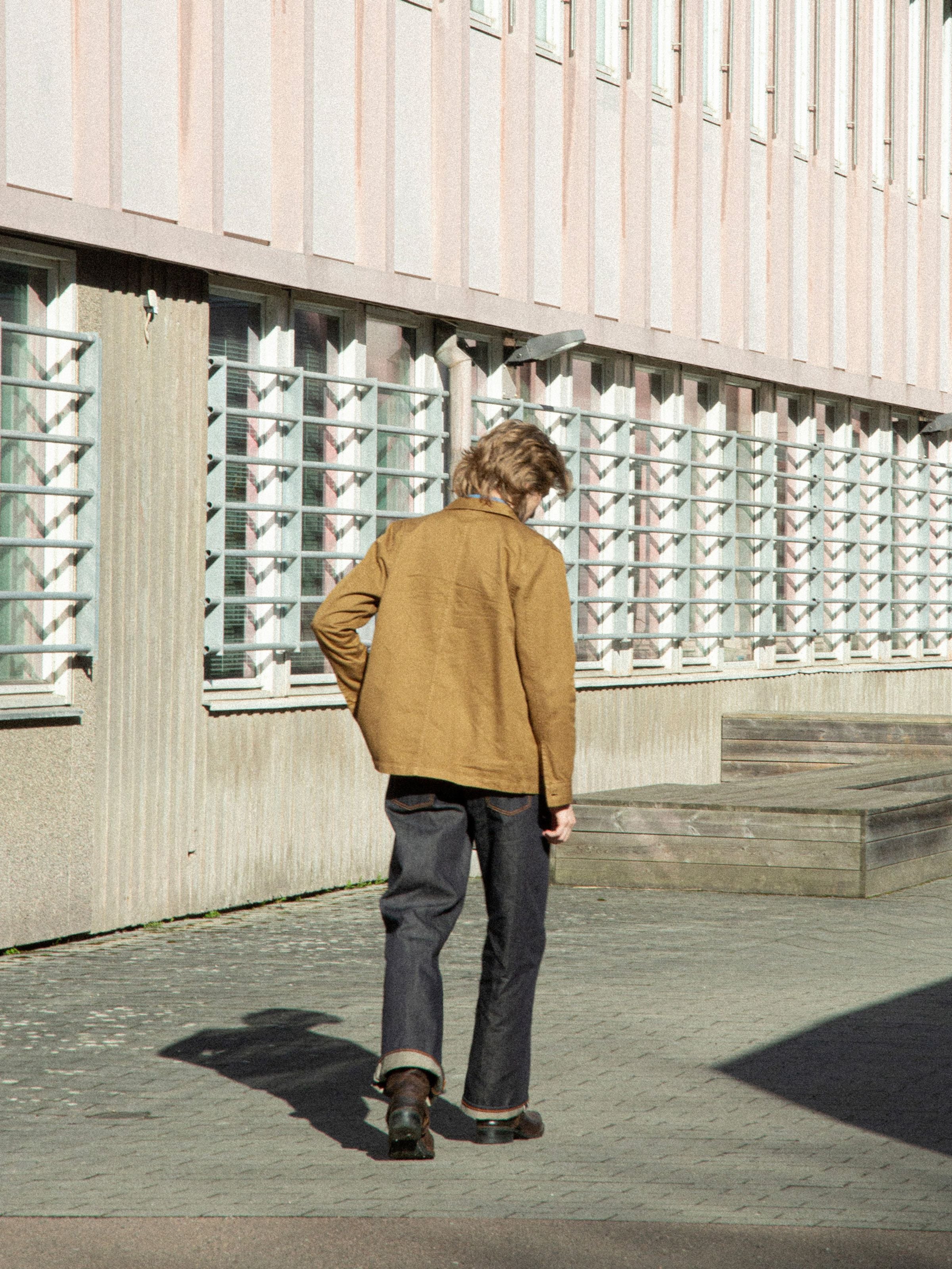 Nudie Jeans Barney Worker Jacket in Braun-Olive, von hinten an einem Model im Freien gezeigt.