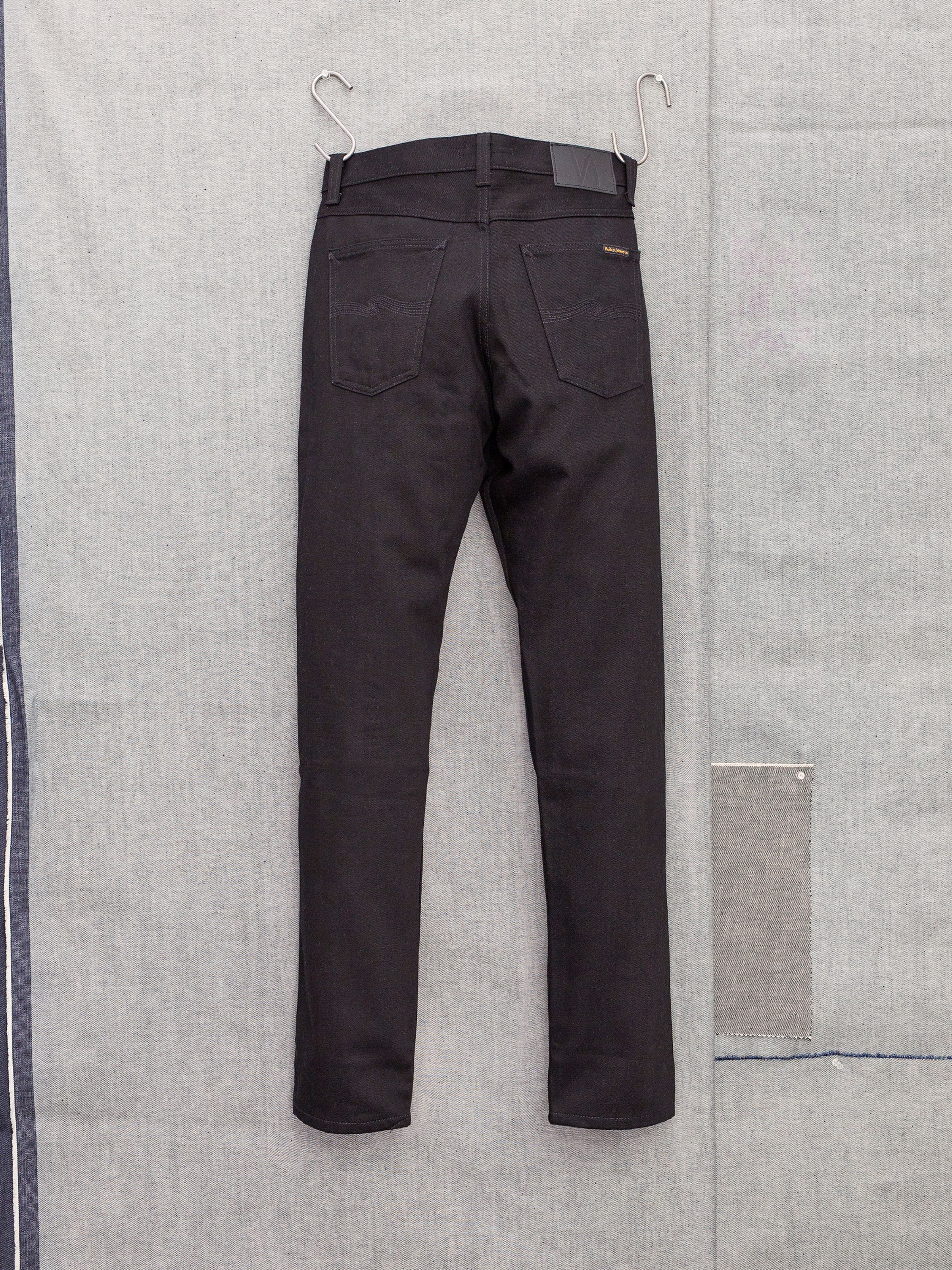 Nudie Jeans Steady Eddie II Dry Everblack, men's regular tapered jeans shown from the back, hanging against a grey backdrop.
