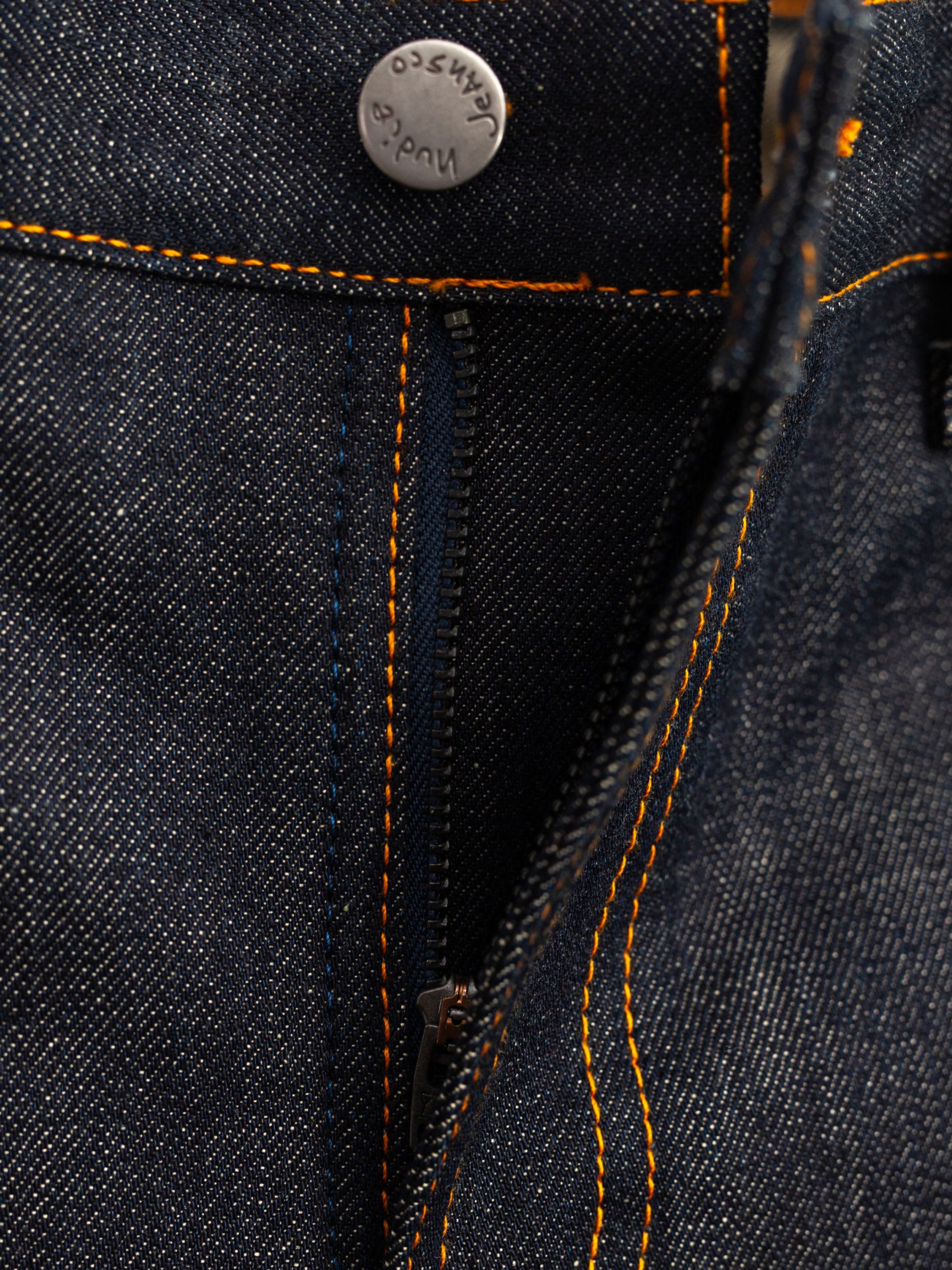 Nudie Jeans Gritty Jackson Dry Selvage, Nahaufnahme des Reißverschlusses und der orangen Nähte auf starrem Selvedge-Denim.