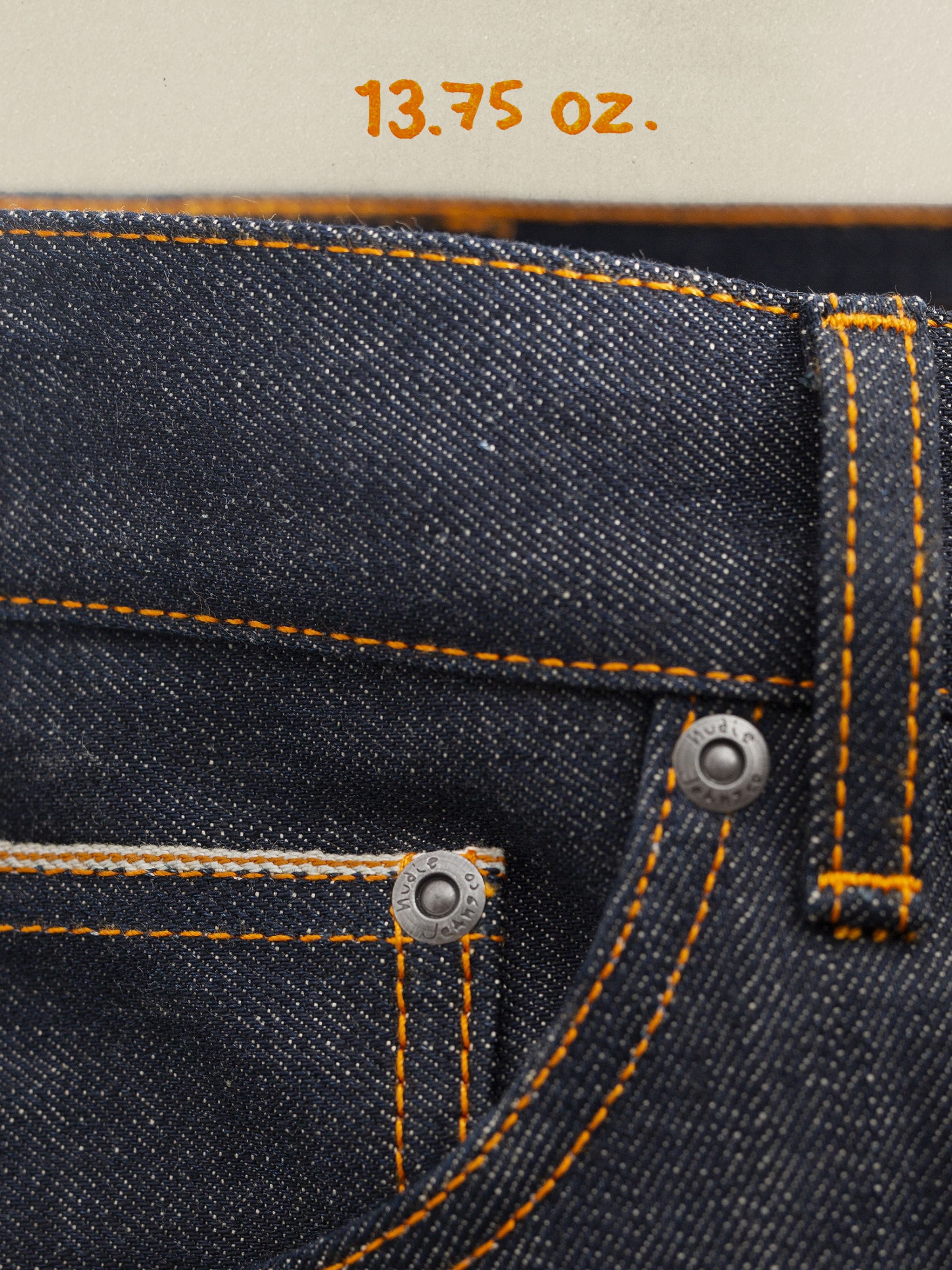 Nudie Jeans Gritty Jackson Dry Selvedge, close-up of the front coin pocket, antique silver rivets, and orange stitching.