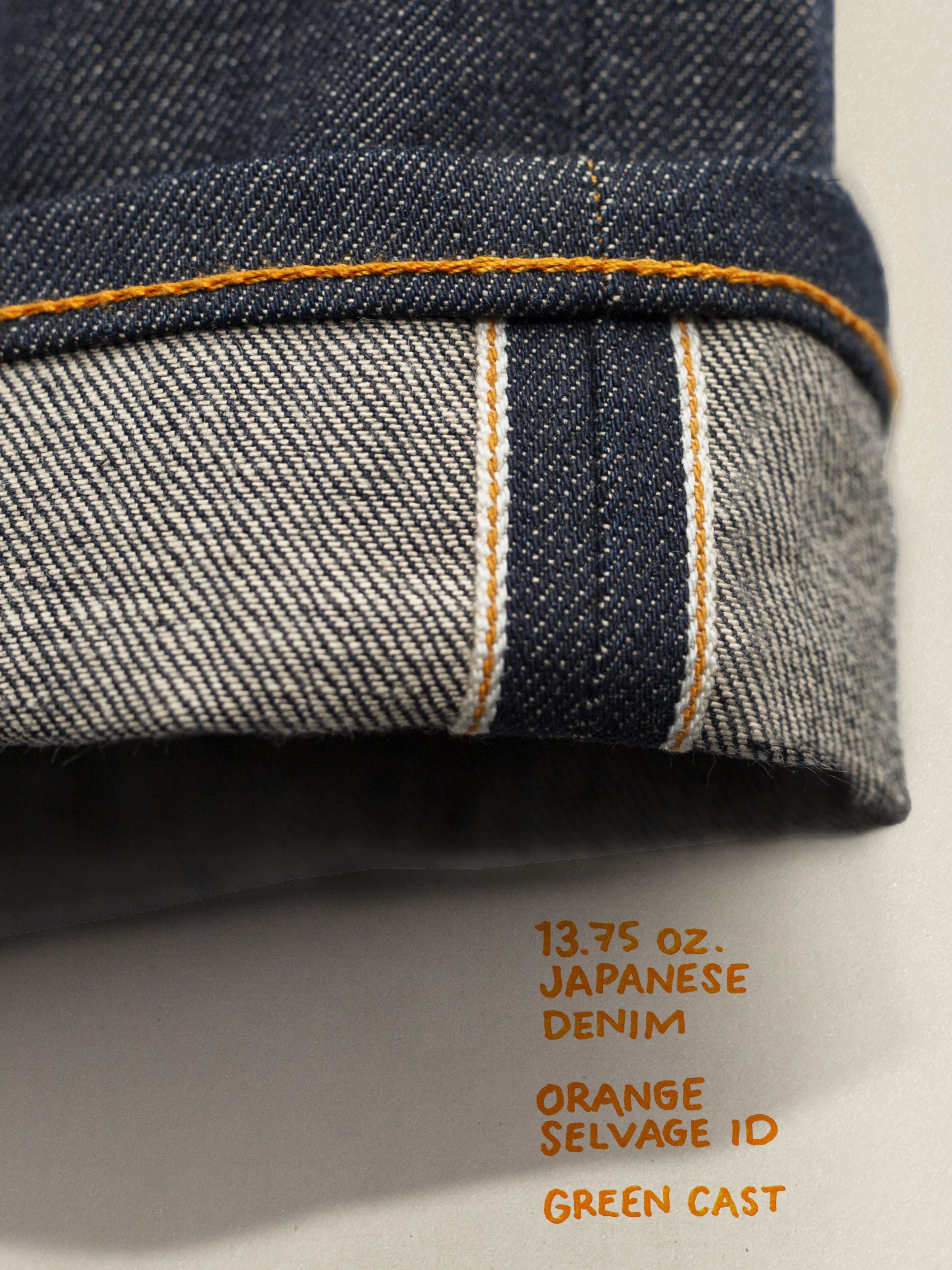 Nudie Jeans Tuff Tony Dry Selvage, close-up of the cuffed hem showing the orange selvedge ID line and organic cotton denim.