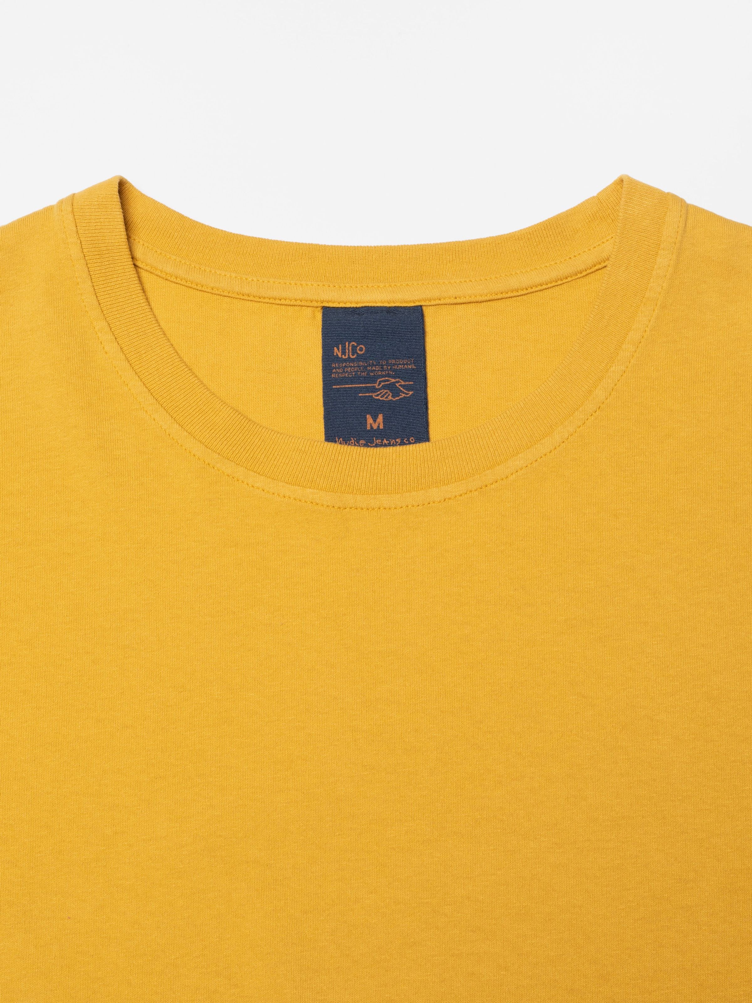 Nudie Jeans Uno Everyday T-Shirt Old Yellow, showing a close-up of the crew neck collar and brand label.