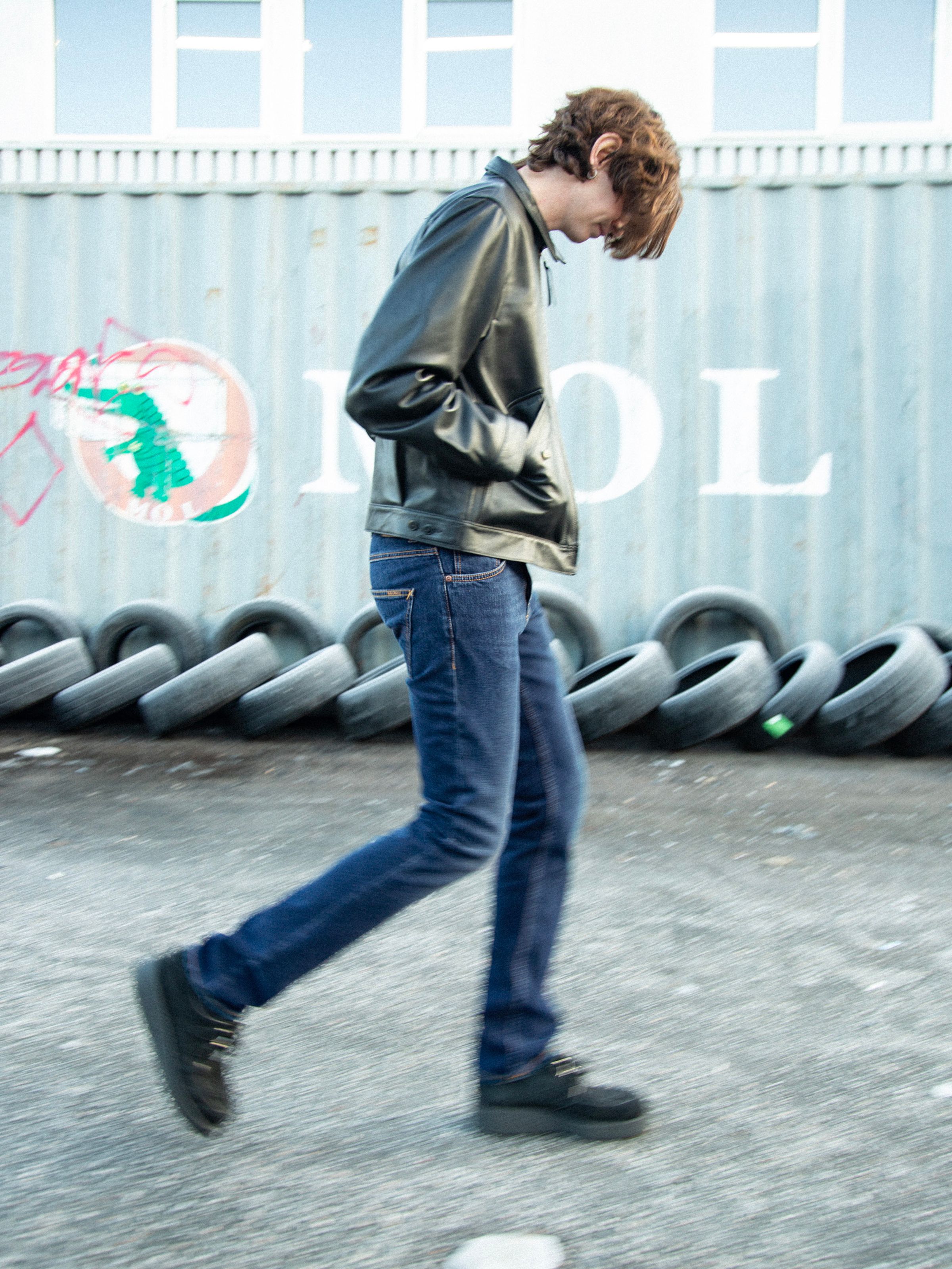 Nudie Jeans Grim Tim New Ink, men's slim fit jeans shown on a walking model in a side view.