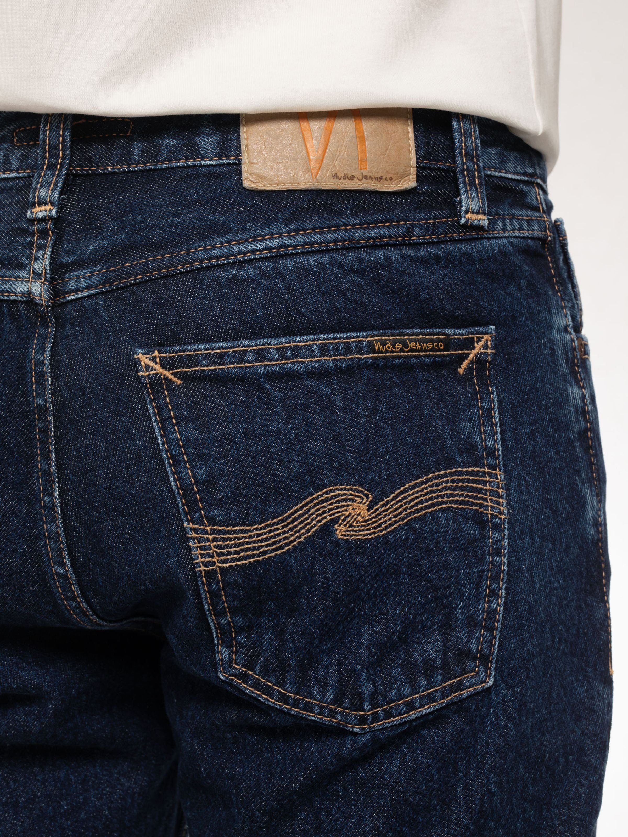 Nudie Jeans Steady Eddie II Heavy Rinse, Nahaufnahme der Gesäßtasche mit tabakfarbenen Nähten und Jacron-Patch.