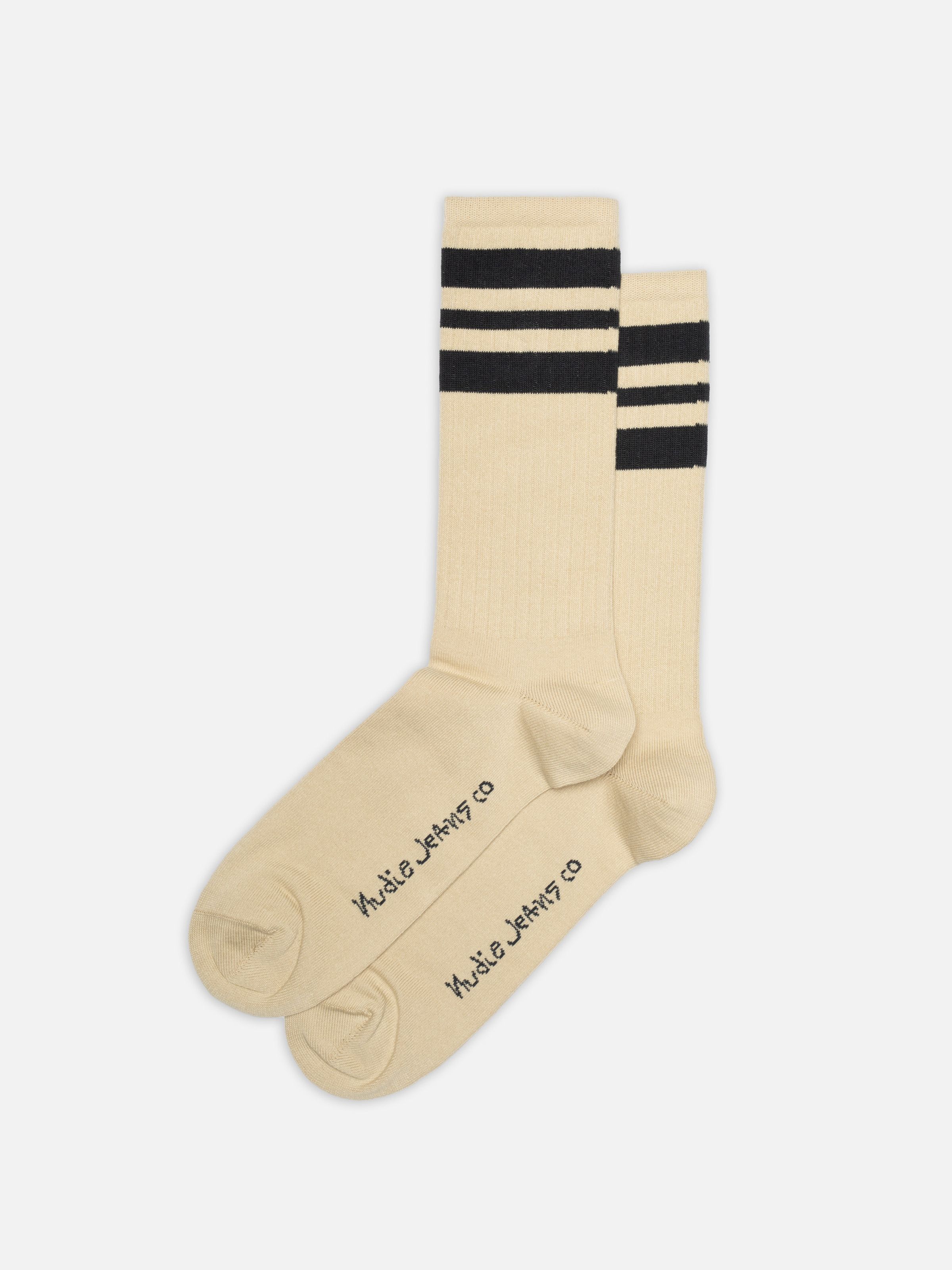 Nudie Jeans Amundsson Sport Socks in Sand, ein Paar Herren-Sportsocken mit schwarzen Streifen oben, flach liegend.