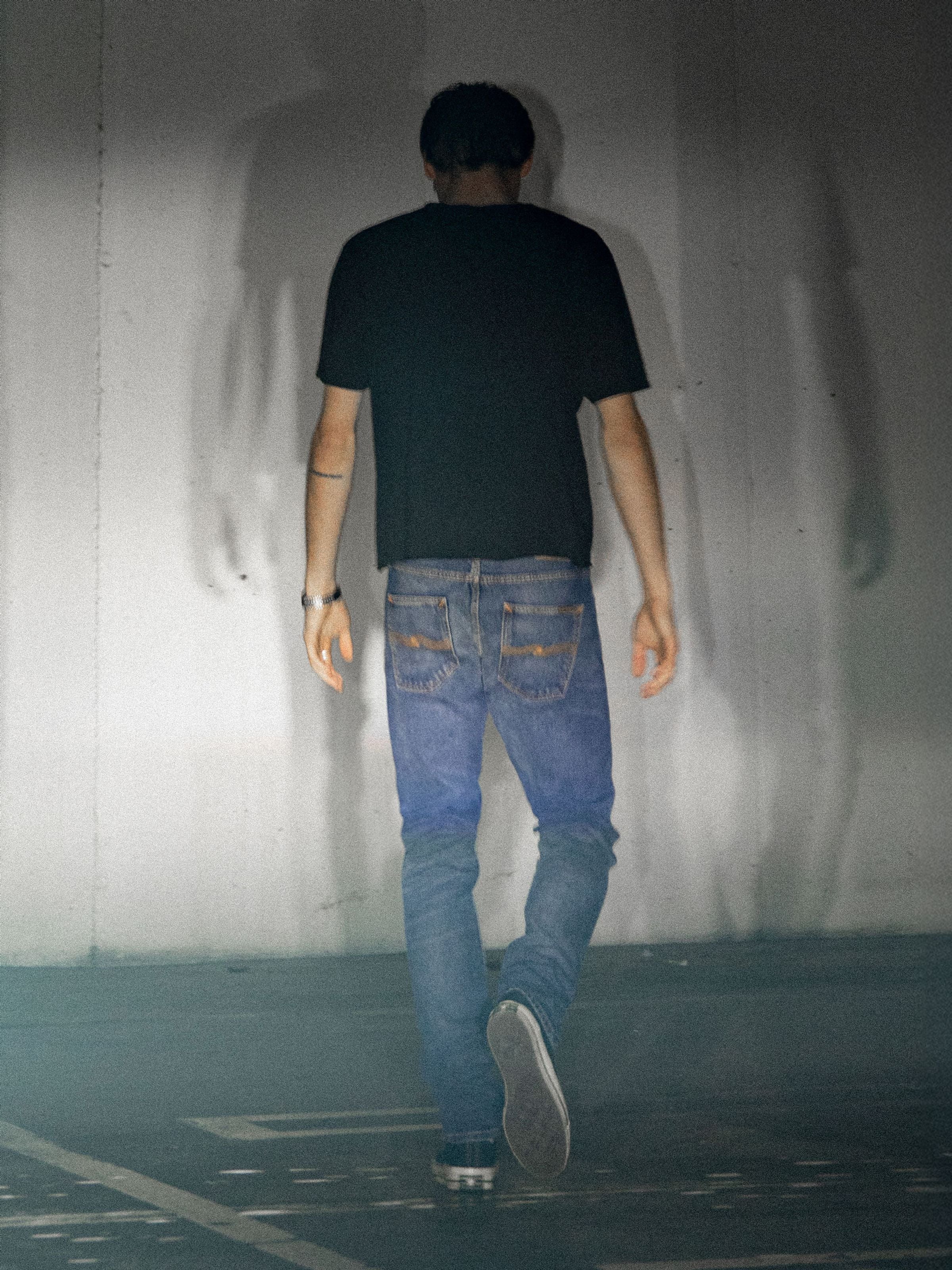 Lean Dean Troubled Sea, men's slim tapered jeans in dark blue wash, shown in a lifestyle shot from behind walking outdoors.