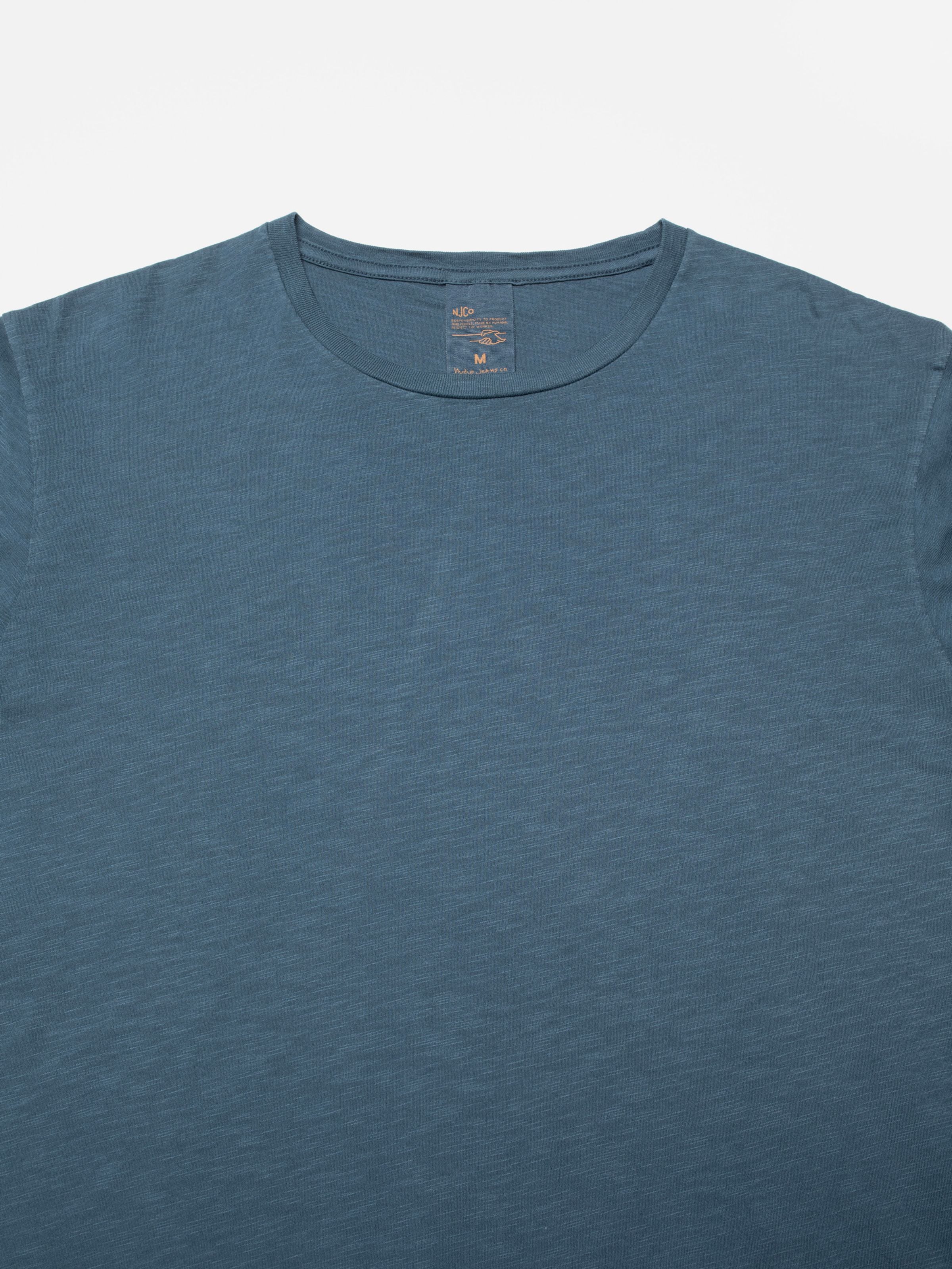 Nudie Jeans Roffe Slub T-Shirt Blue, a men's regular fit t-shirt, shown laid flat with a close-up on the collar.