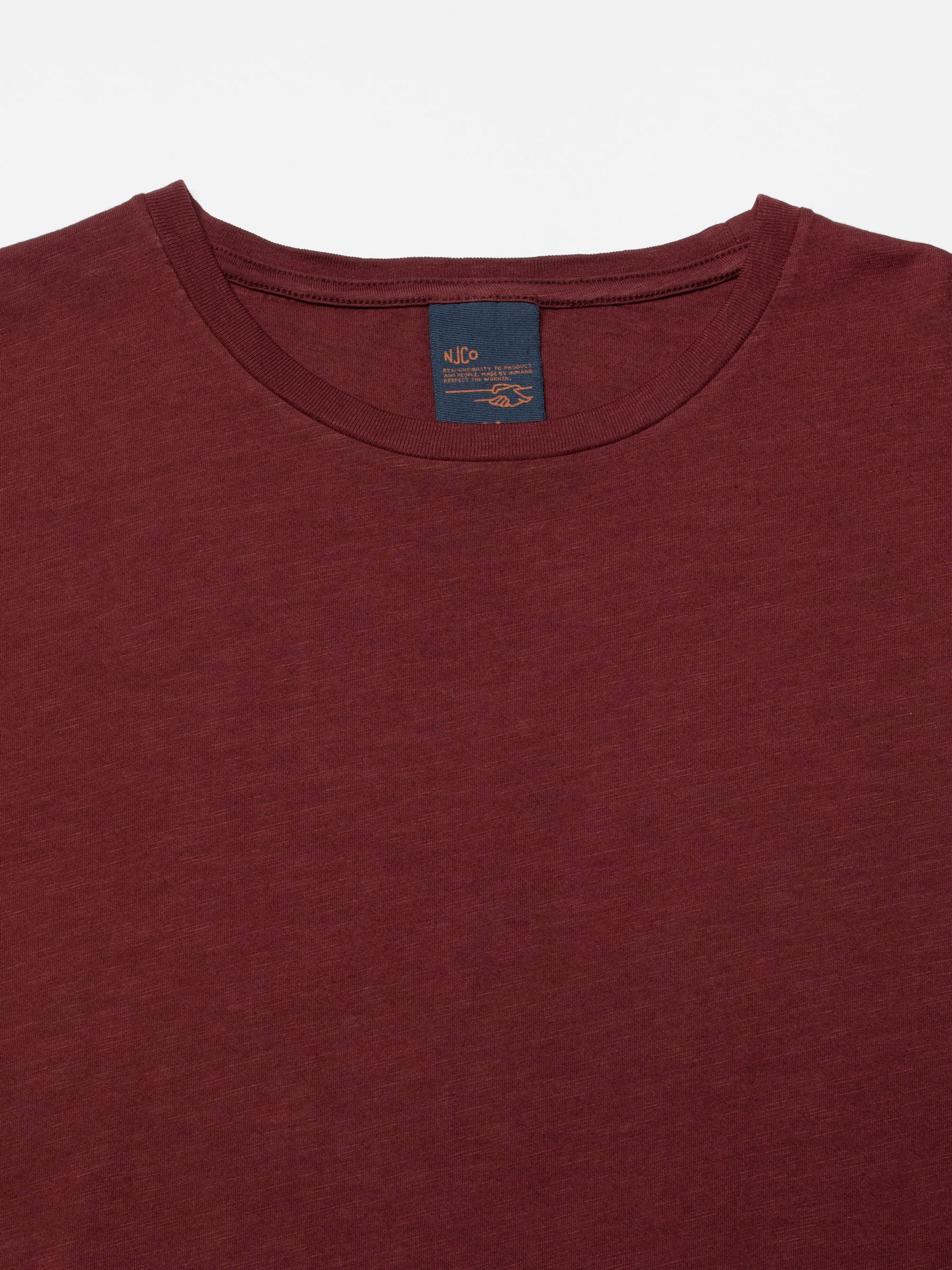 Nudie Jeans Roffe Slub T-Shirt in Burgundy, close-up of the ribbed crew neck and organic cotton jersey.