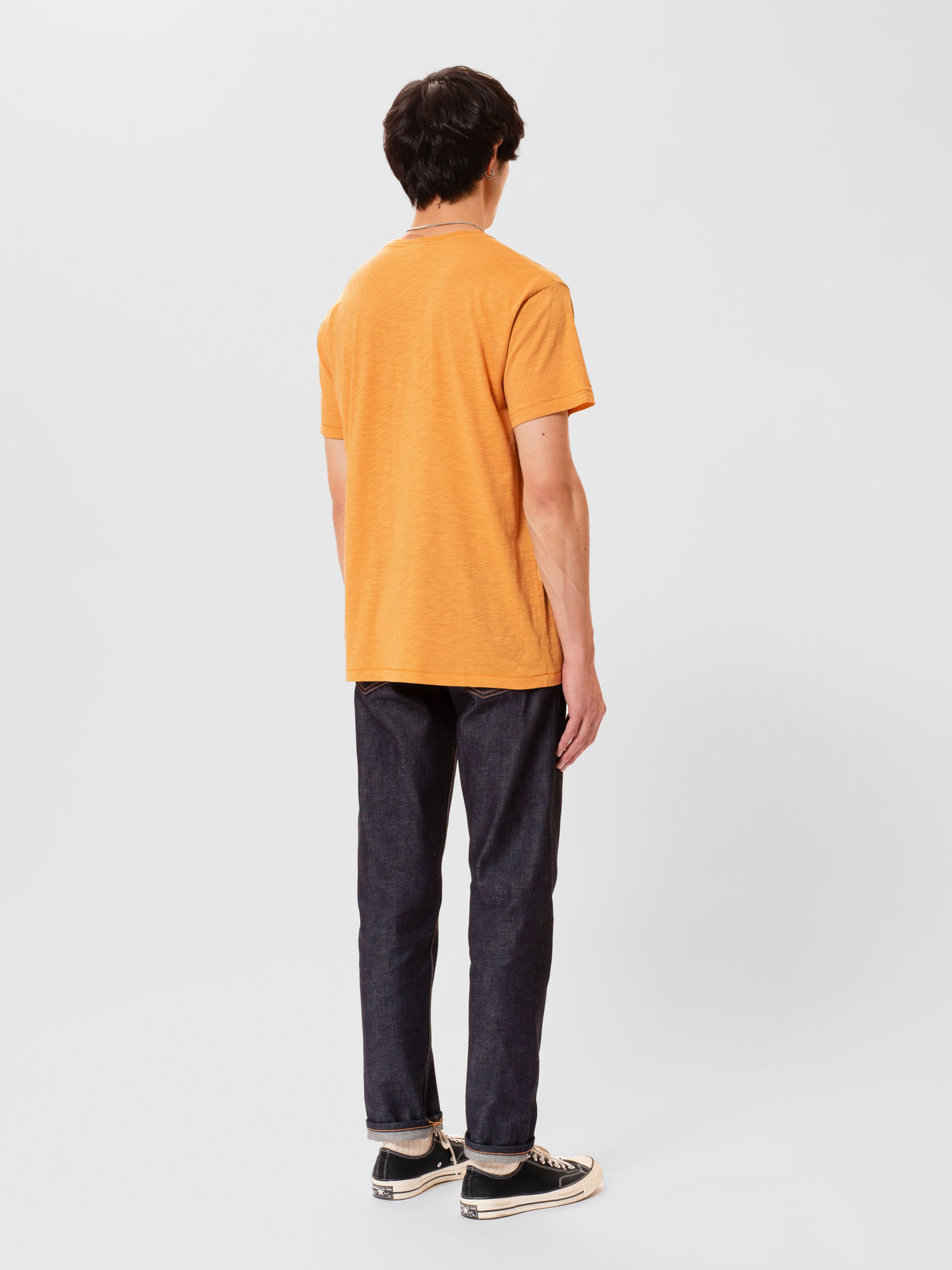 Nudie Jeans Roffe T-shirt in Ochre, a men's regular fit t-shirt shown on a model from the back.