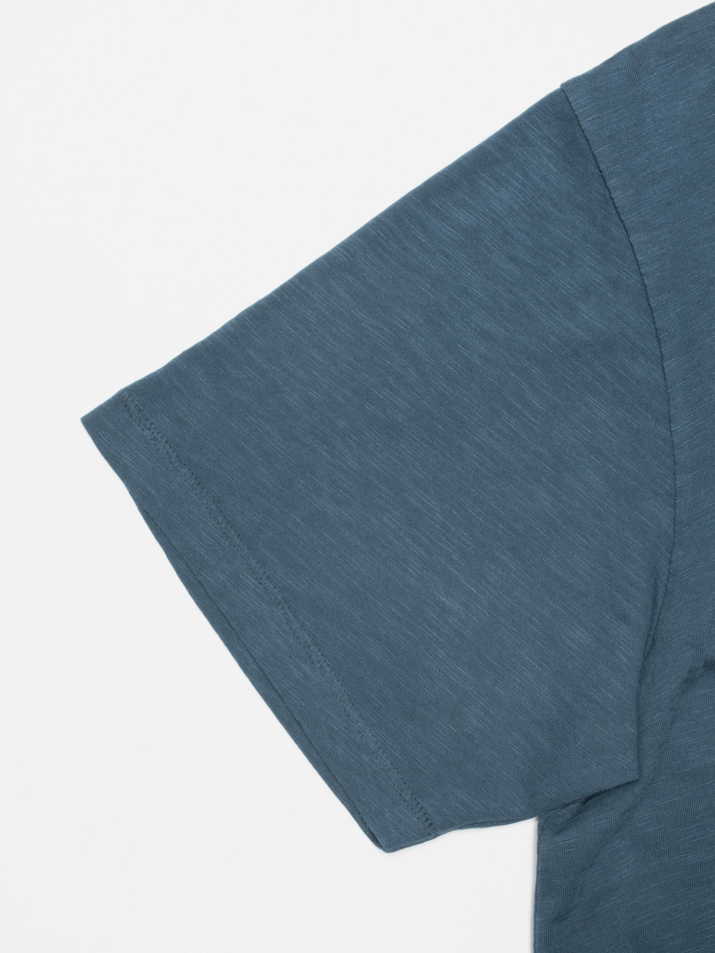 Nudie Jeans Roffe Slub T-Shirt in blue, a men's regular fit t-shirt, shown in a close-up detail of the sleeve.
