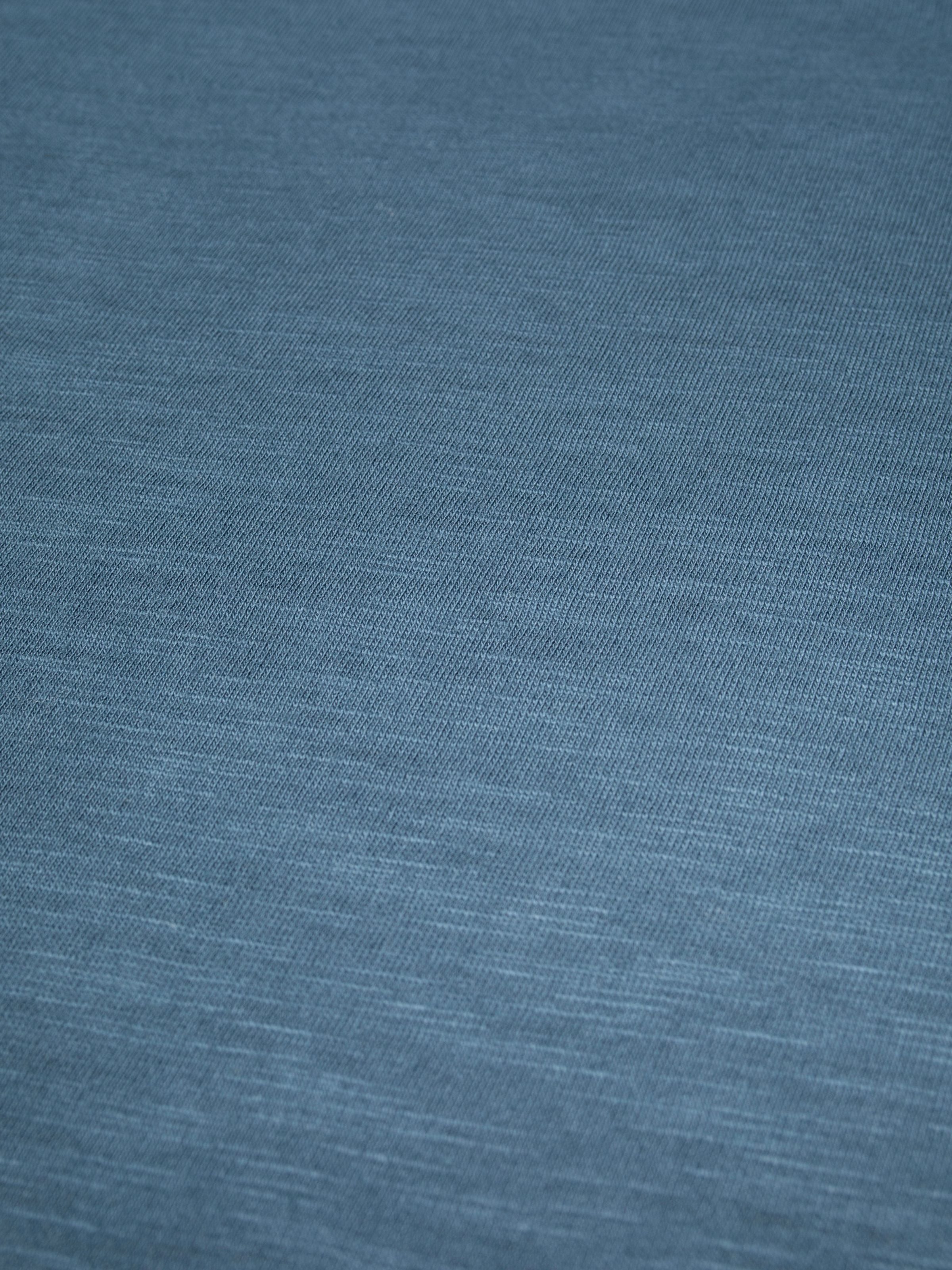 Nudie Jeans Roffe Slub T-Shirt in blue, showing a close-up of the slubby organic cotton jersey fabric.