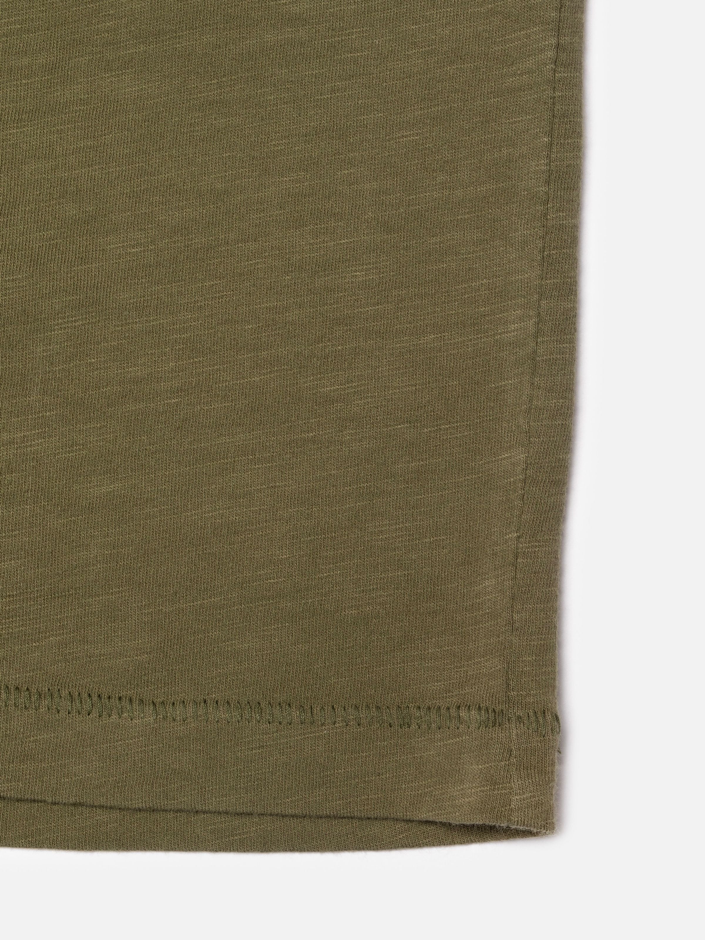 Nudie Jeans Roffe Slub T-Shirt in Olive Green, showing a close-up of the hem and organic cotton slub texture.