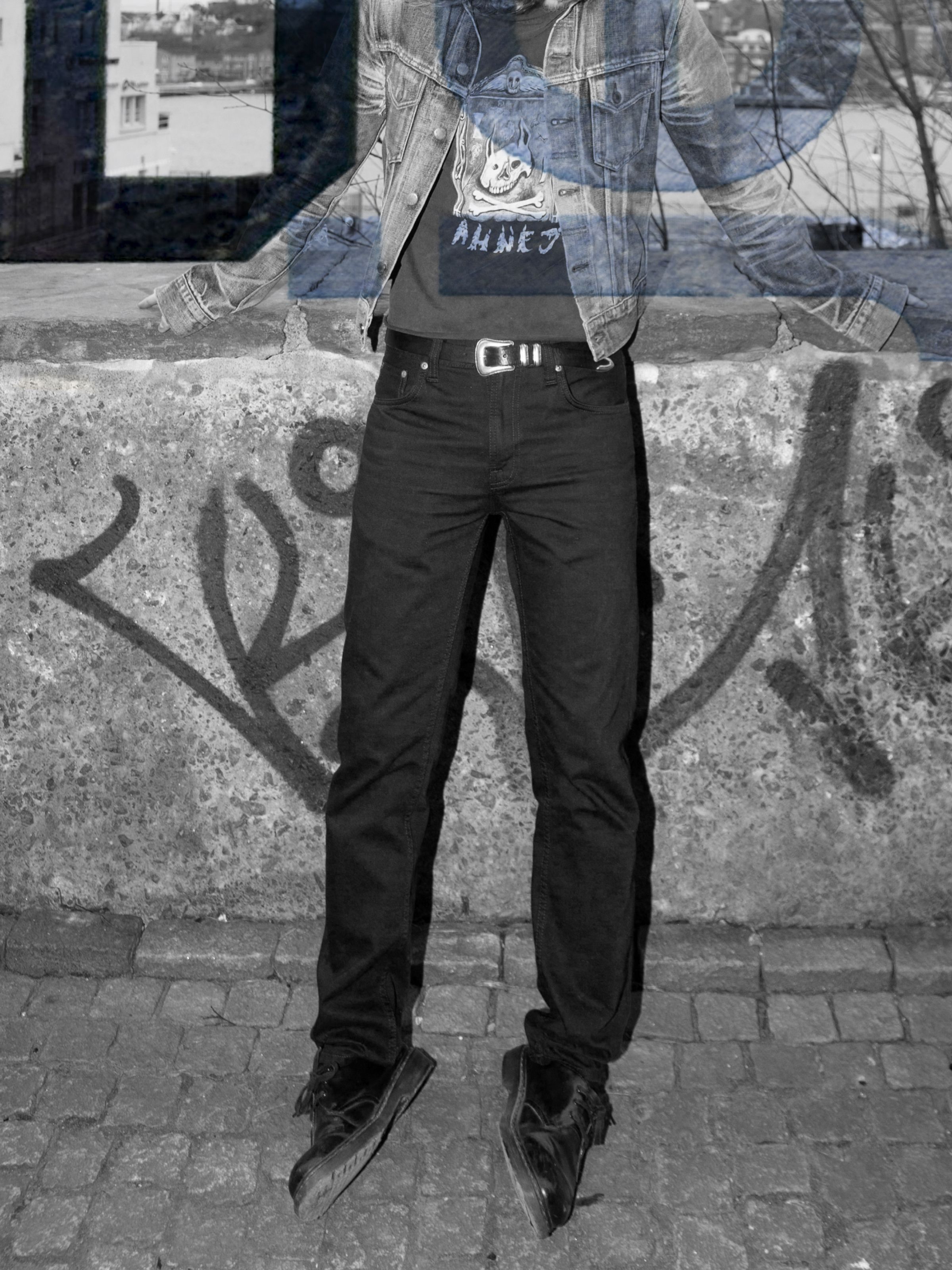 Nudie Jeans Gritty Jackson Dry Everblack, men's regular fit jeans shown on a model jumping in an urban setting.