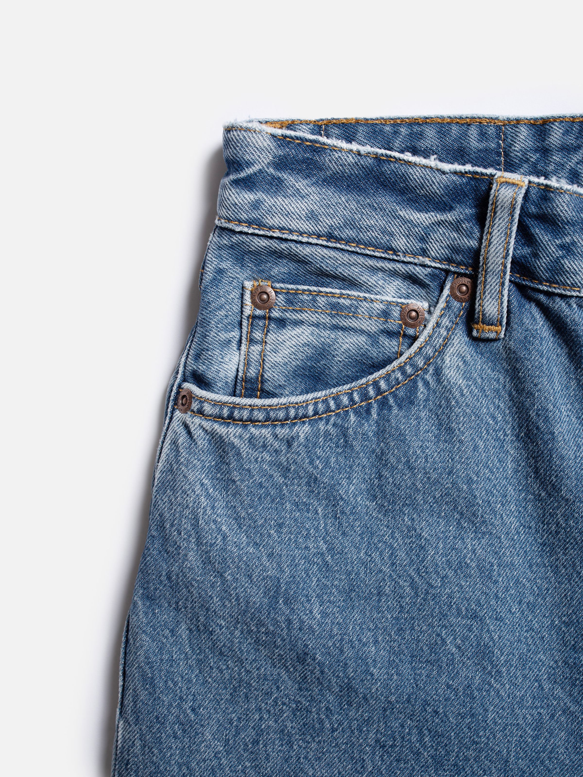 Nudie Jeans Breezy Britt Casual Blue, close-up of the front pocket on mid-blue rigid denim with a 90s marble texture.