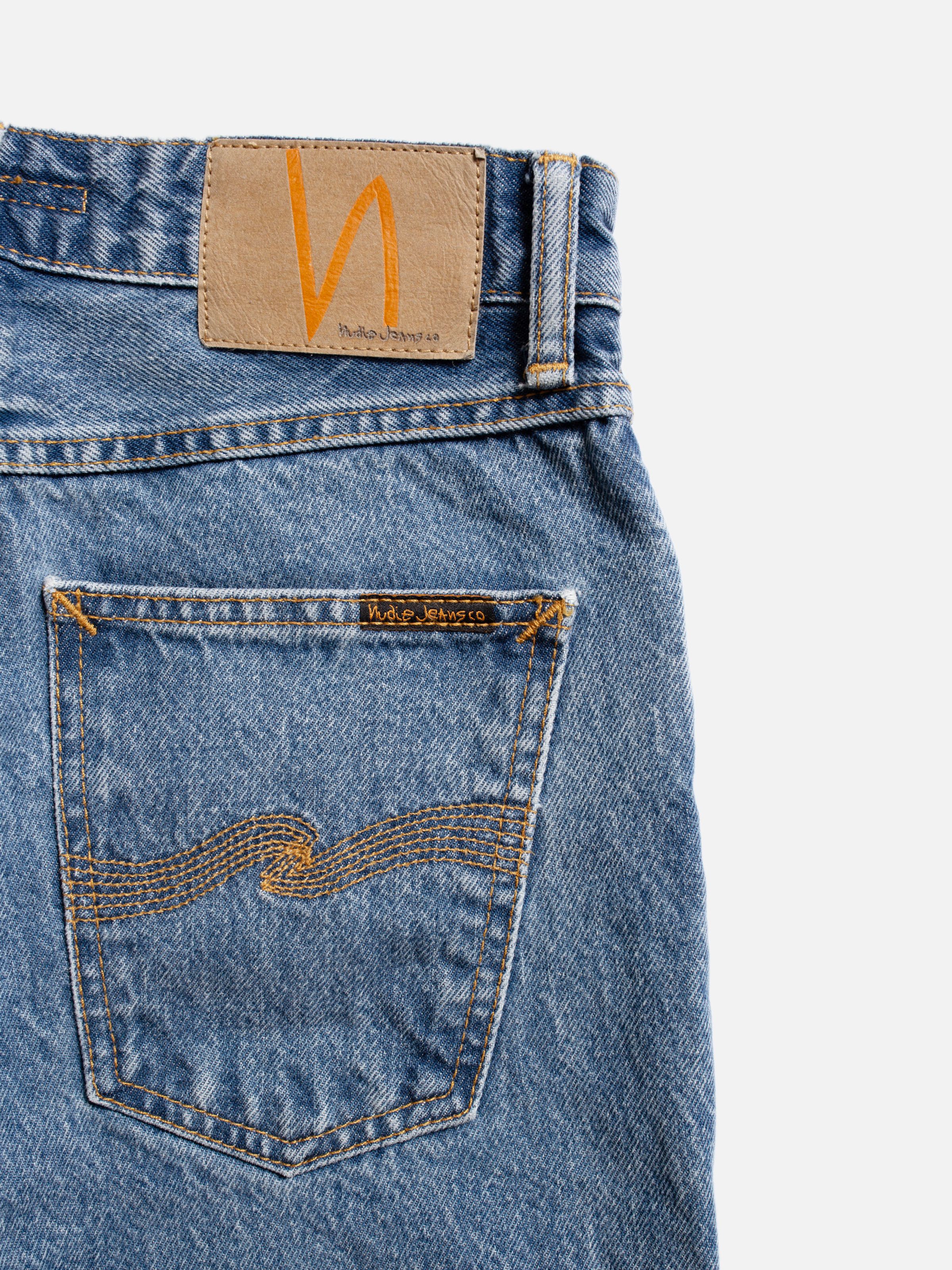 Nudie Jeans Breezy Britt Casual Blue, close-up of the back pocket and Jacron patch on mid-blue stonewash rigid denim.