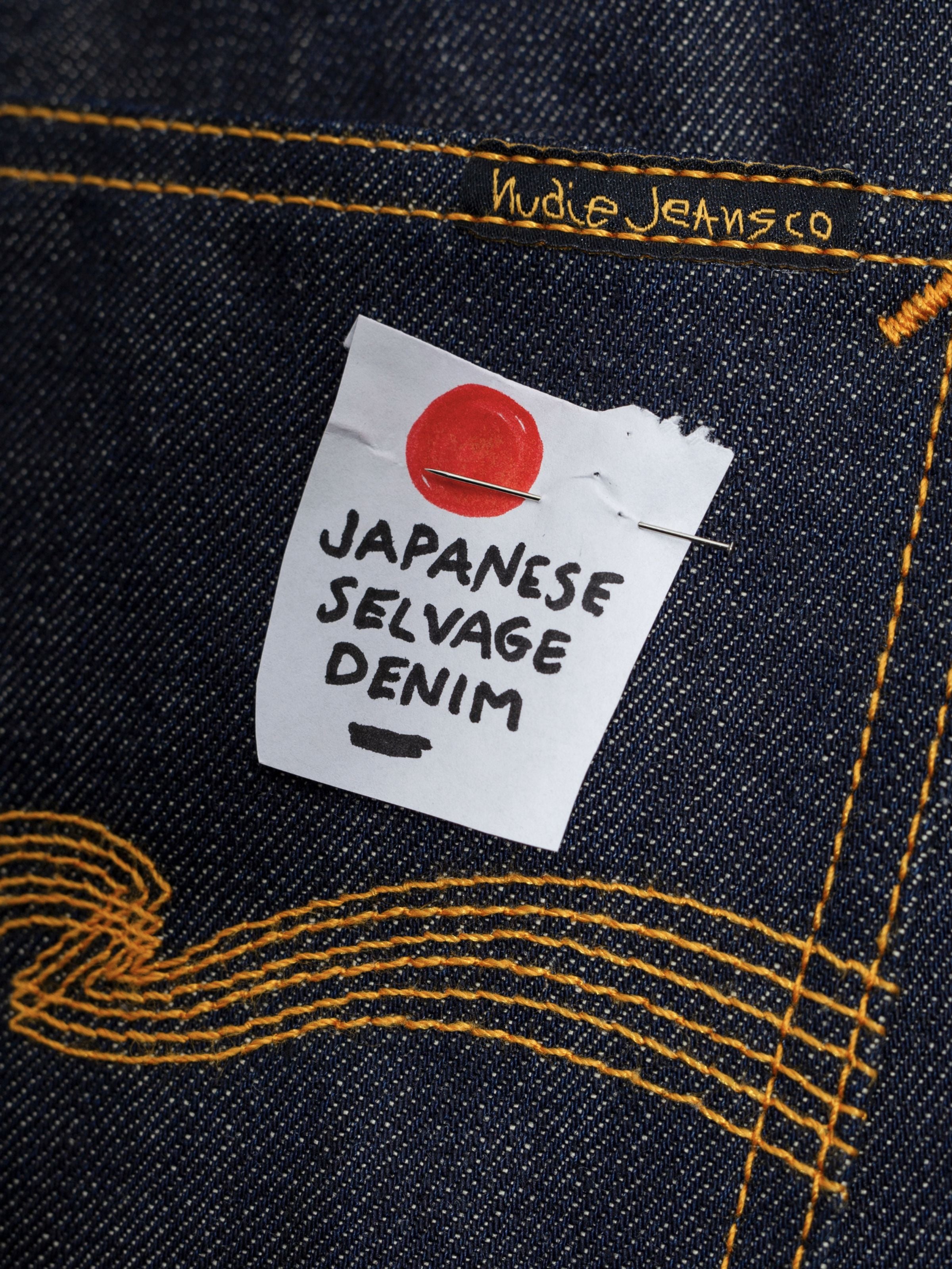 Nudie Jeans Rad Rufus Dry Selvage, close-up of dark denim with a note pinned on reading Japanese selvedge denim.