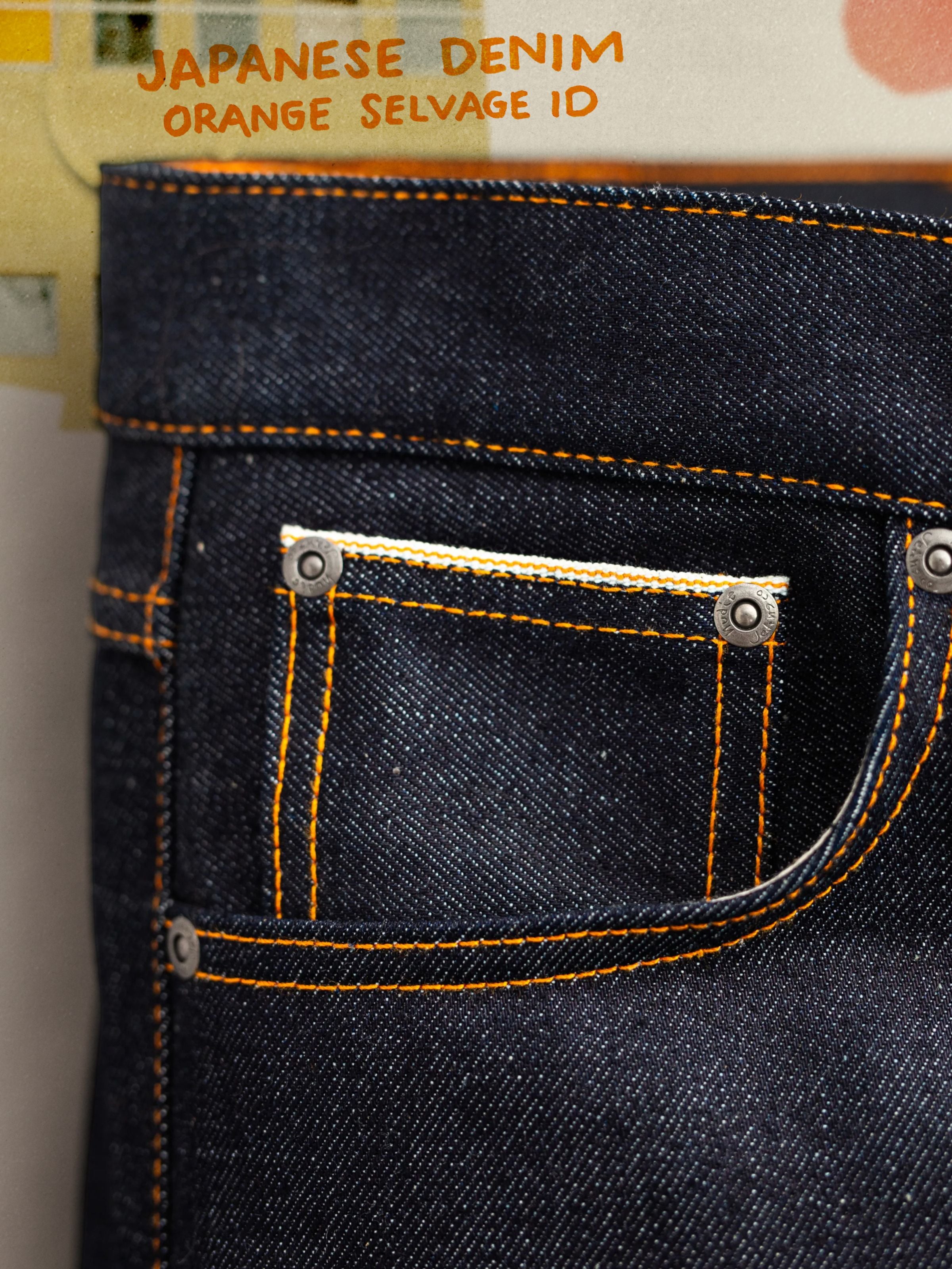 Nudie Jeans Grim Tim Dry Japan Selvage, showing a close-up of the front coin pocket, orange stitching, and dark indigo denim.