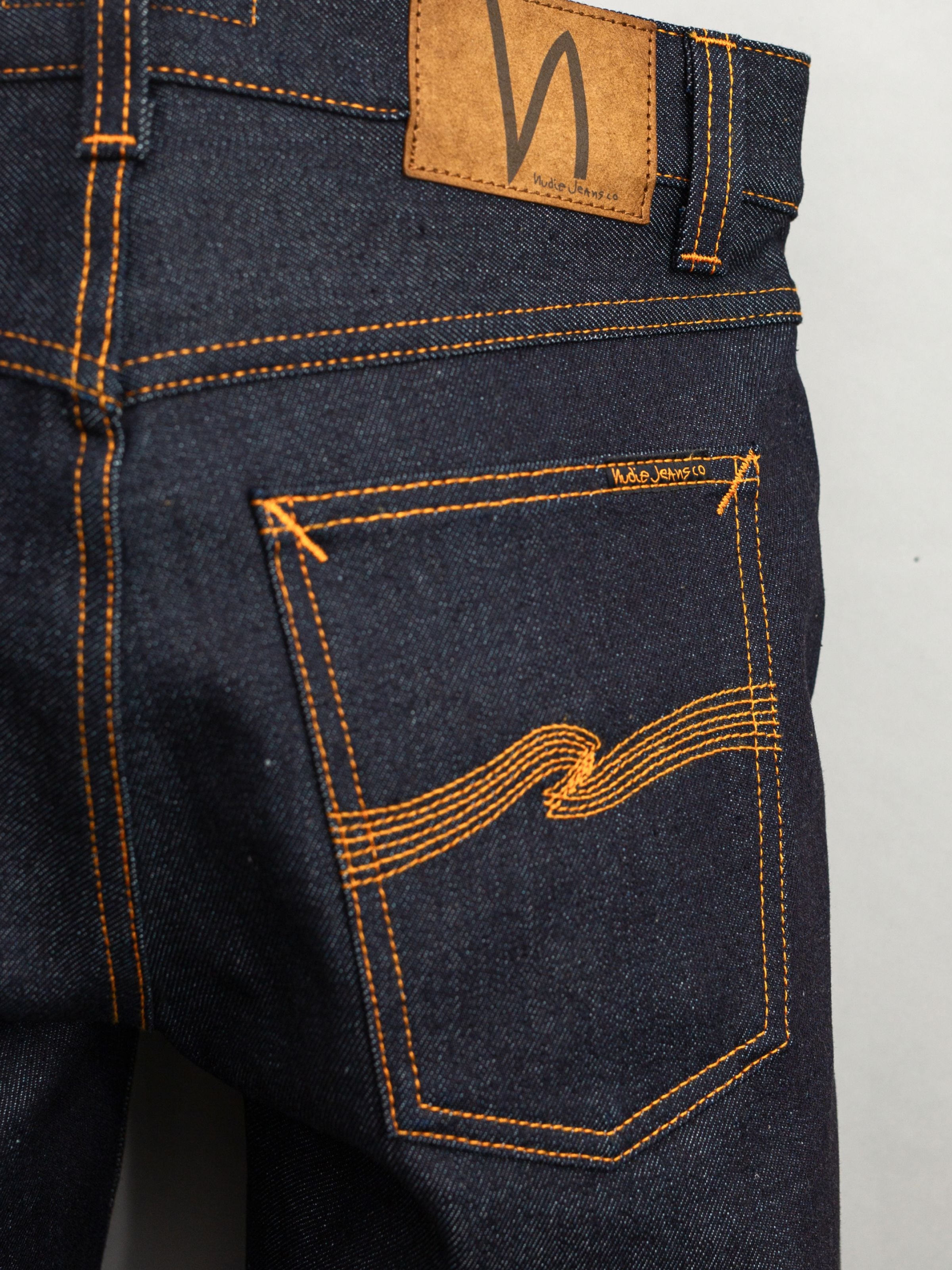 Nudie Jeans Solid Ollie Dry Japan Selvage, showing the back pocket, orange stitching, and dark selvedge denim texture.
