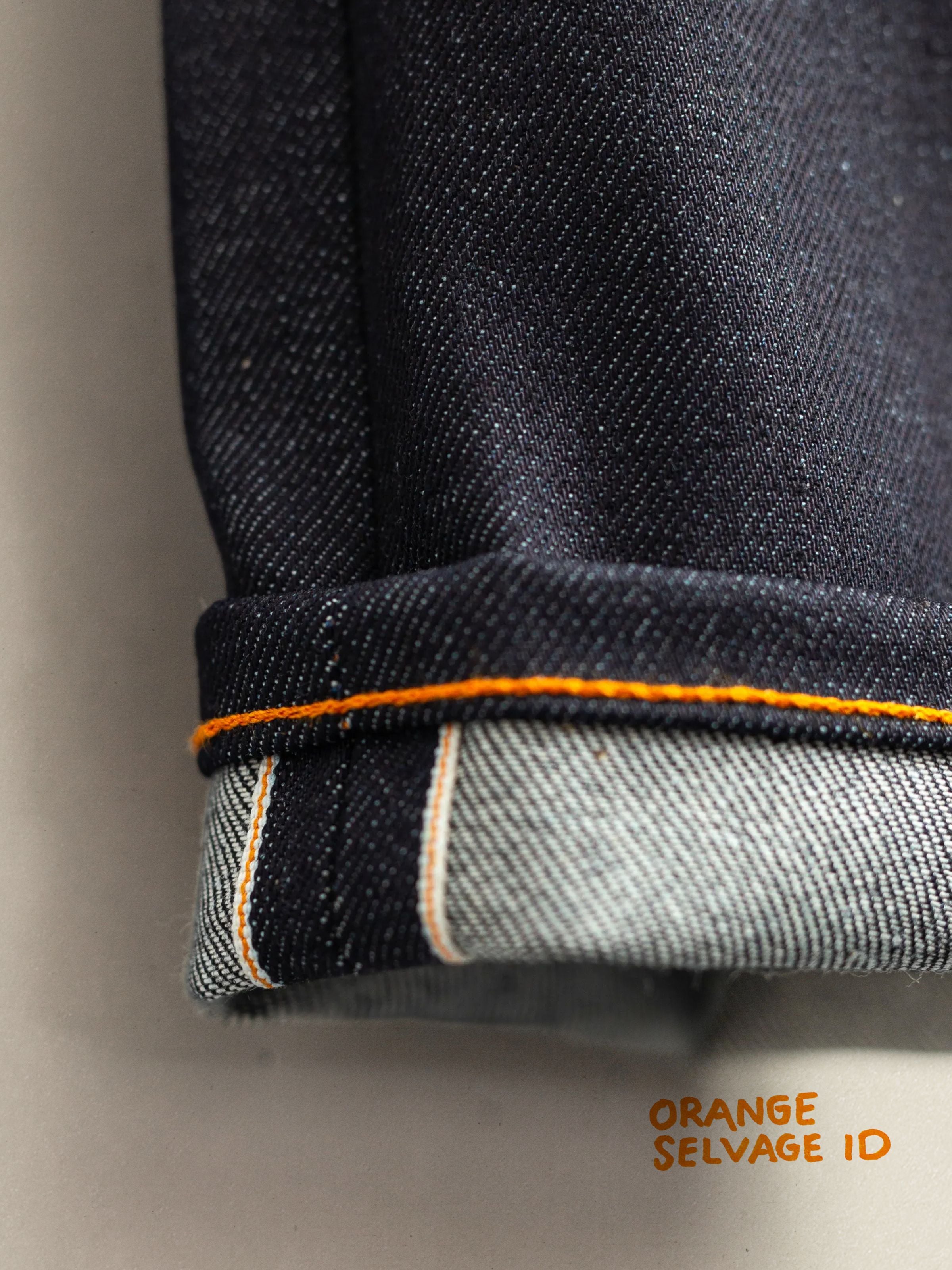 Nudie Jeans Solid Ollie Dry Japan Selvage, close-up of the cuffed hem showing the orange-line selvedge denim texture.