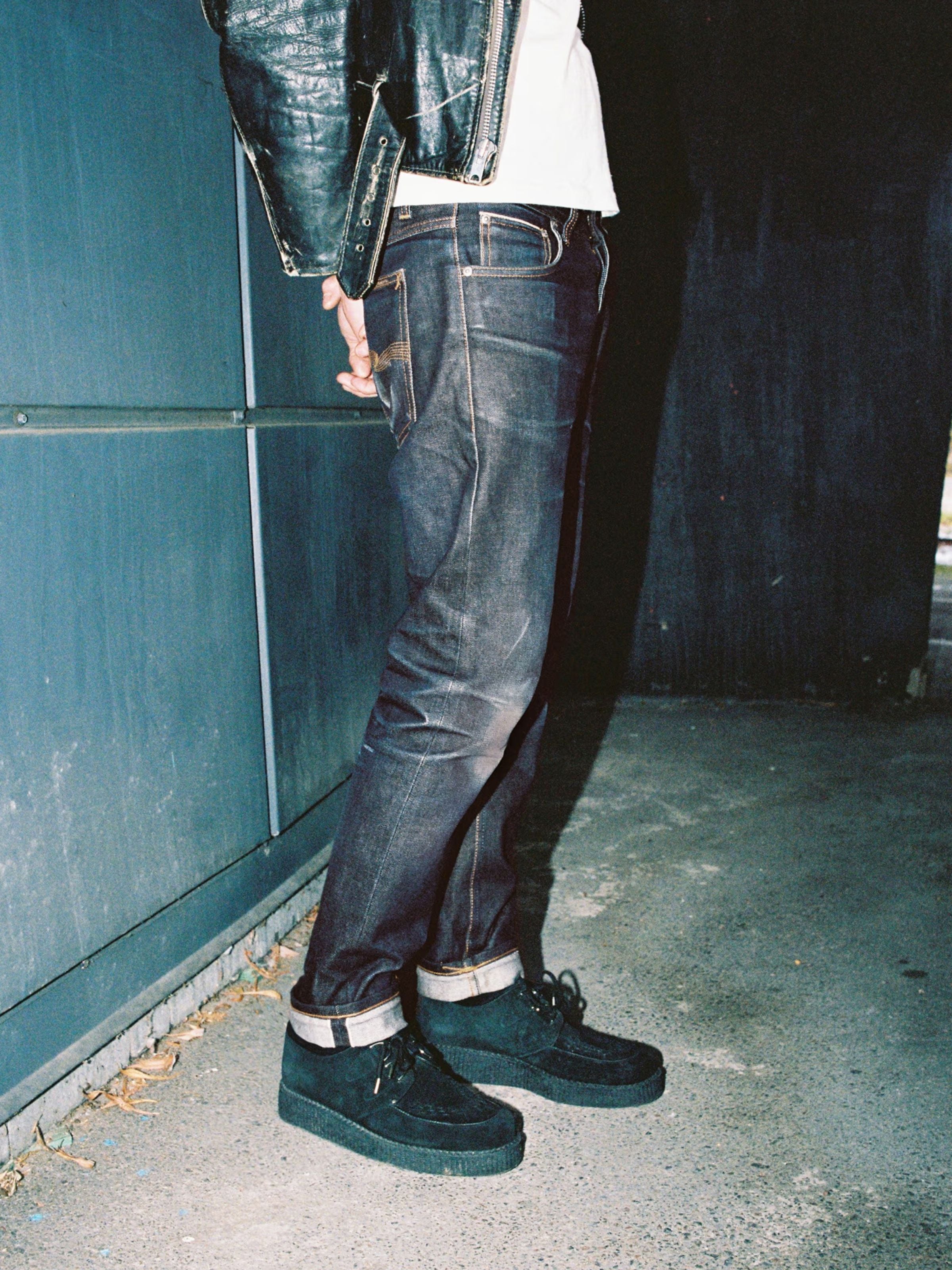 Nudie Jeans Solid Ollie Dry Japan Selvedge, slim fit men's jeans in dark indigo selvedge denim, shown in a lifestyle shot.
