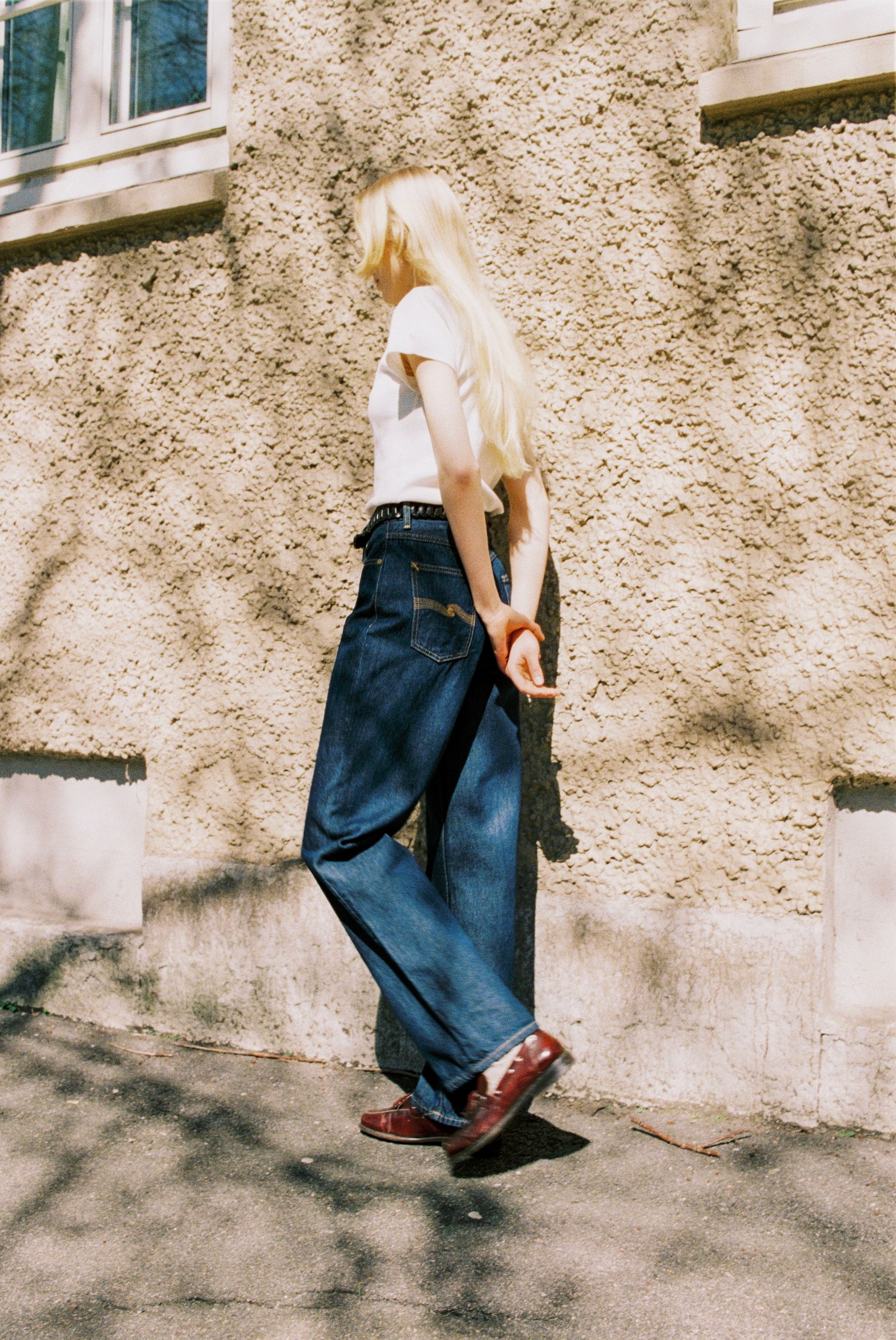 Nudie Jeans Clean Eileen Classic Blue, women's wide-leg organic cotton jeans shown from the side against a wall.