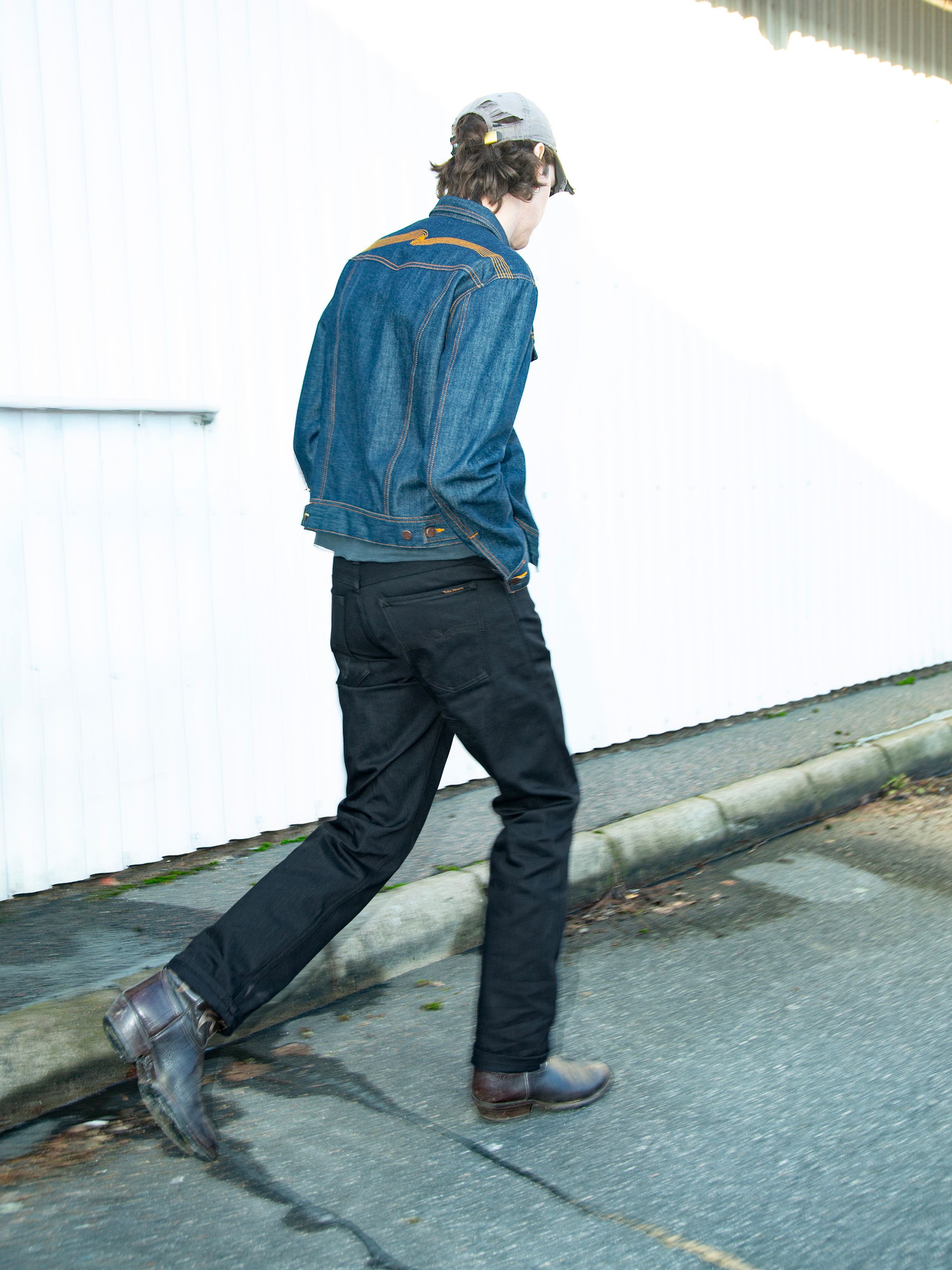 Nudie Jeans Rad Rufus Dry Black Selvage, men's regular fit straight leg jeans shown from the back on a model walking.