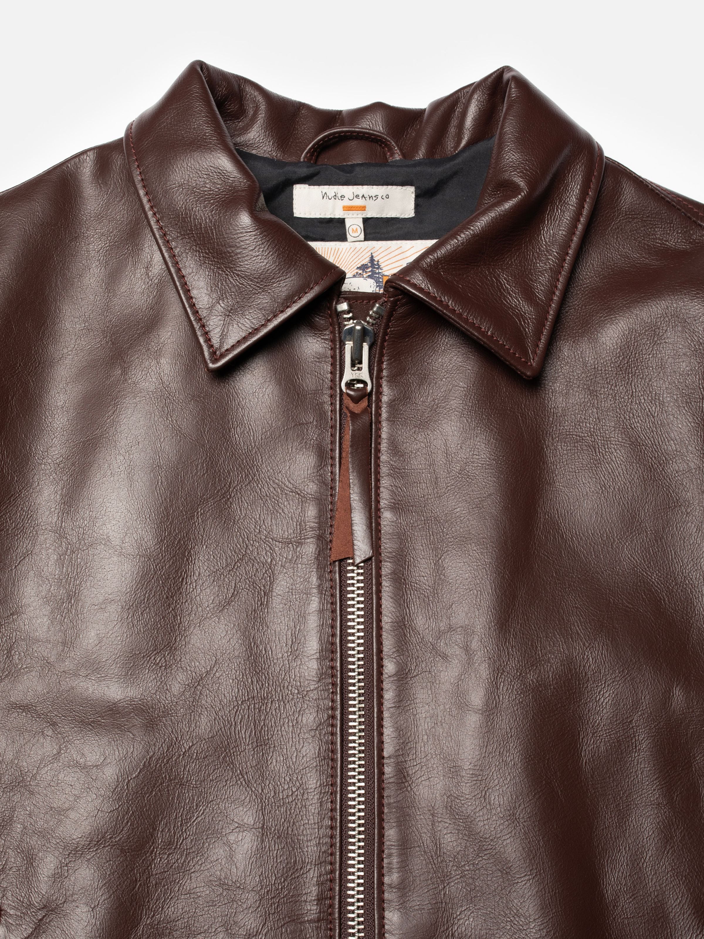 Nudie Jeans Eddy Rider Lederjacke Bordeauxrot, Nahaufnahme von Spitzkragen und silbernem Metall-Frontreißverschluss.