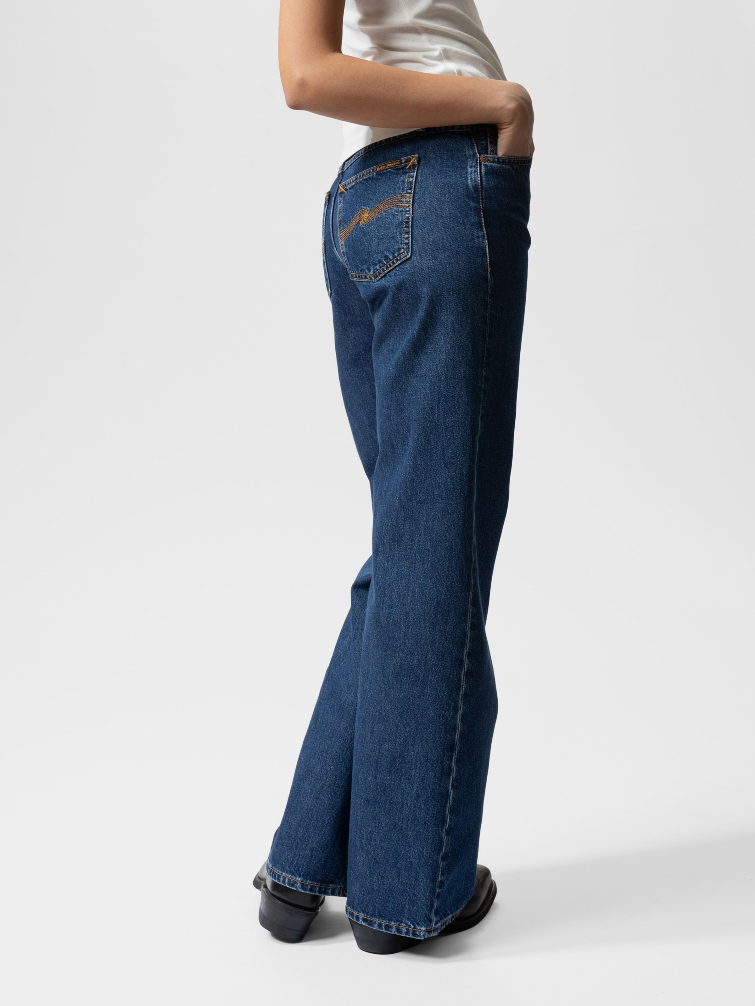 Nudie Jeans Wide Heidi Evening Jazz, women's wide-leg jeans in dark blue stonewash shown from the side on a model.