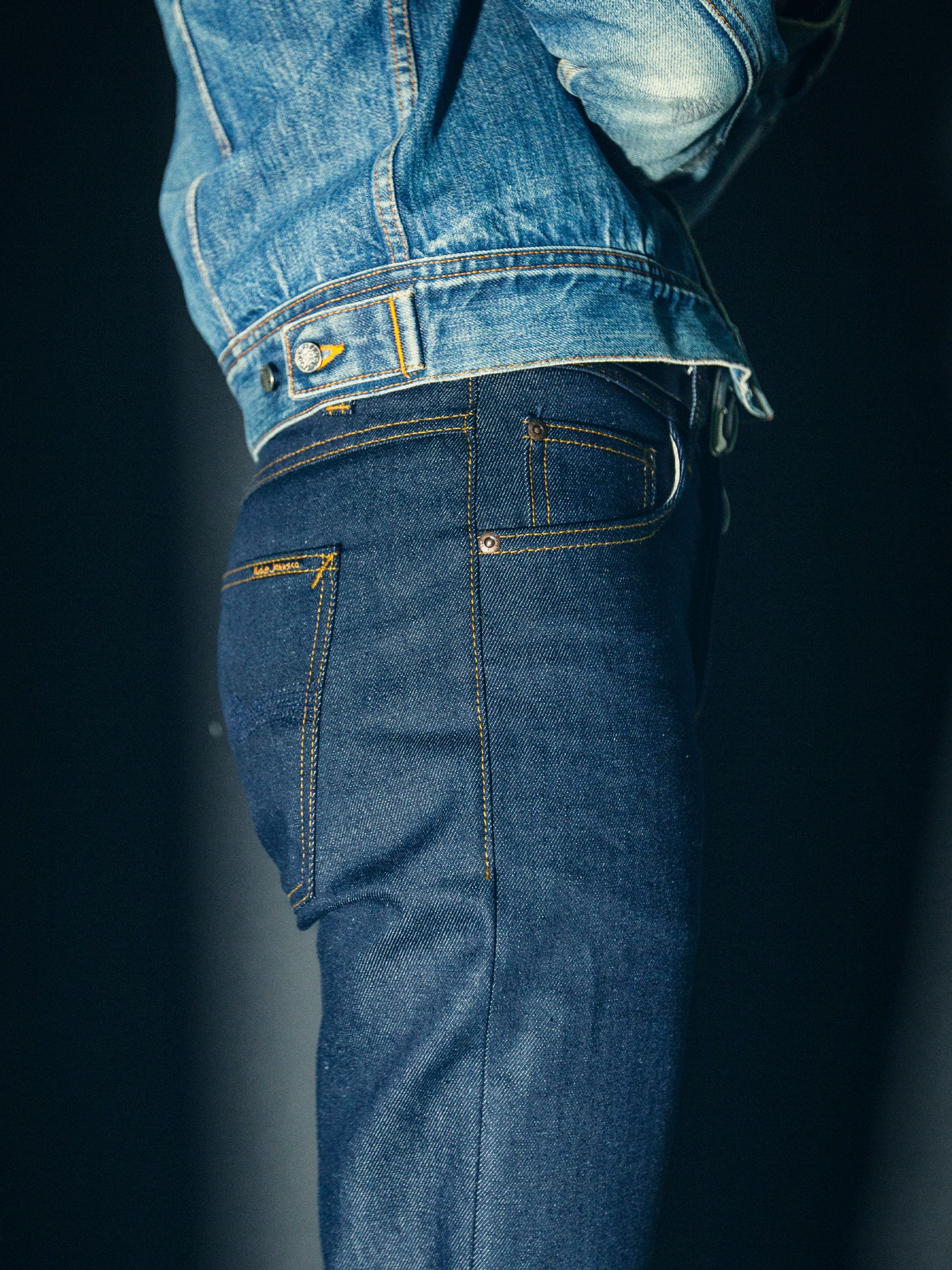 Nudie Jeans Solid Ollie Dry Abyss, close-up side view on a model showing the back pocket, waistband, and dark dry denim.
