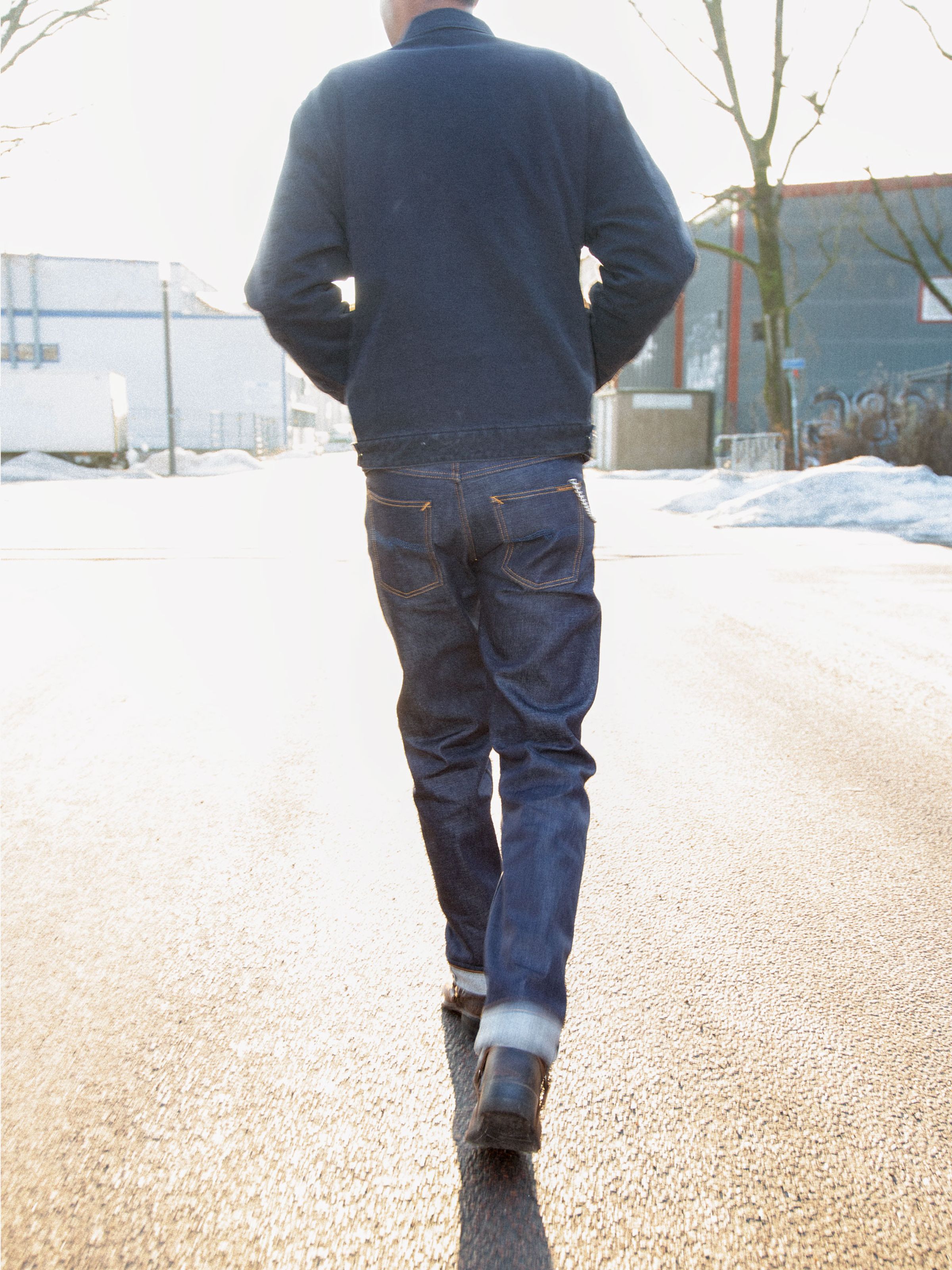 Nudie Jeans Rad Rufus Dry Ace Selvage, men's regular straight fit jeans shown from the back on a model walking down a street.