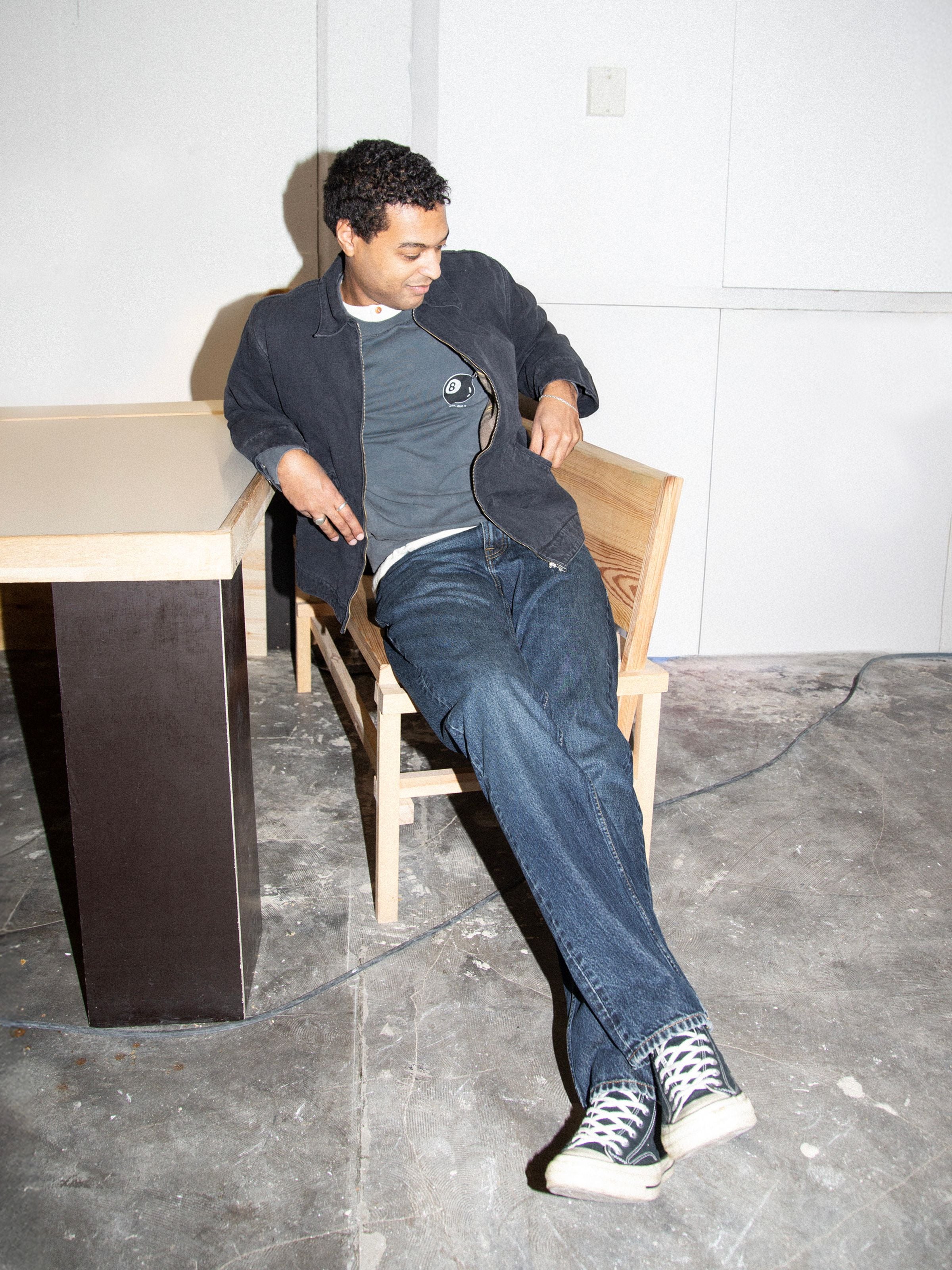 Nudie Jeans Rad Rufus Blue Soil, Herrenjeans mit normaler Passform und geradem Bein, an einem sitzenden Model auf dem Stuhl.