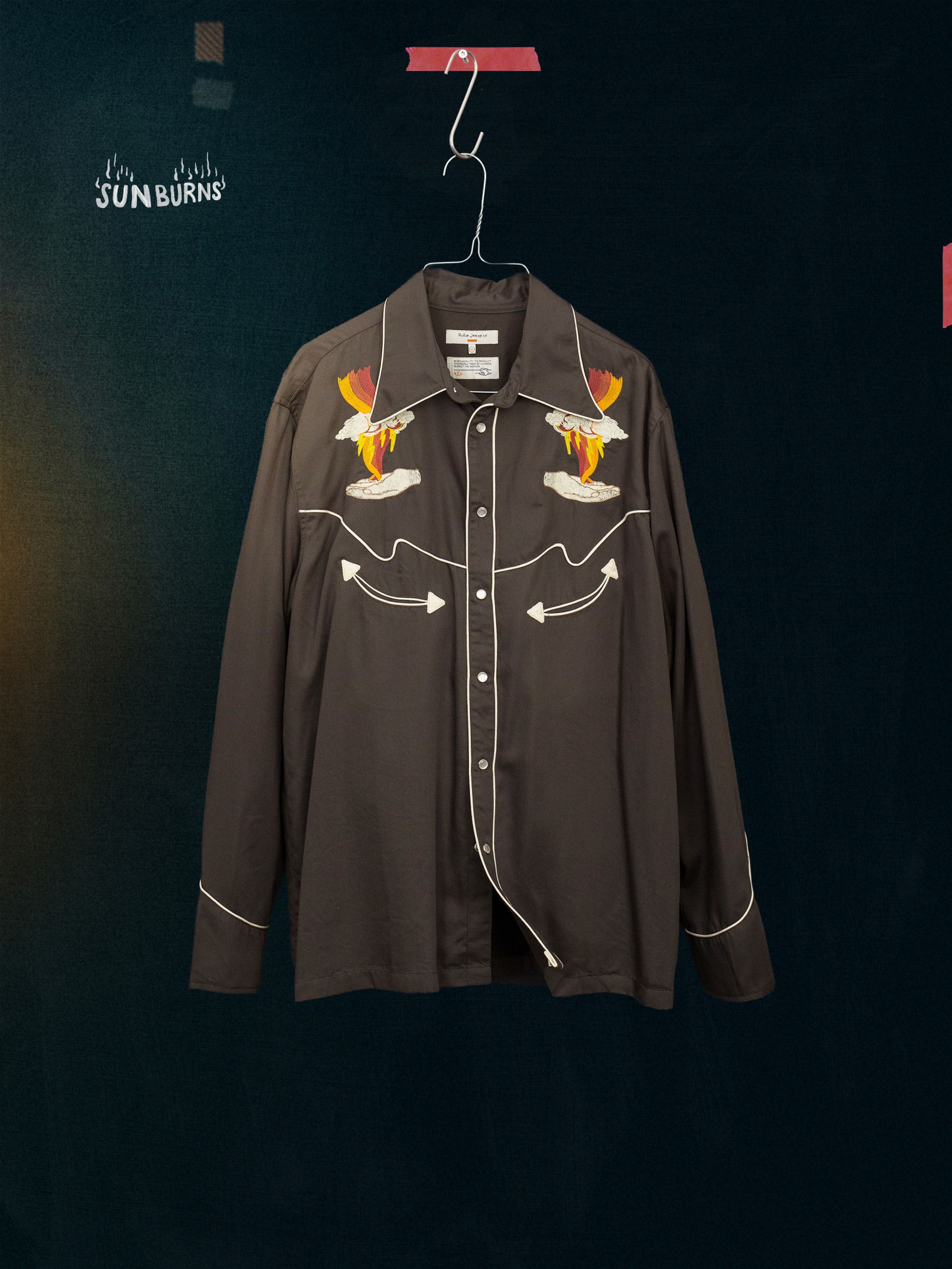 Nudie Jeans Gonzo Western Shirt Sunburns, a men's brown embroidered Western shirt, shown hanging on a hanger.