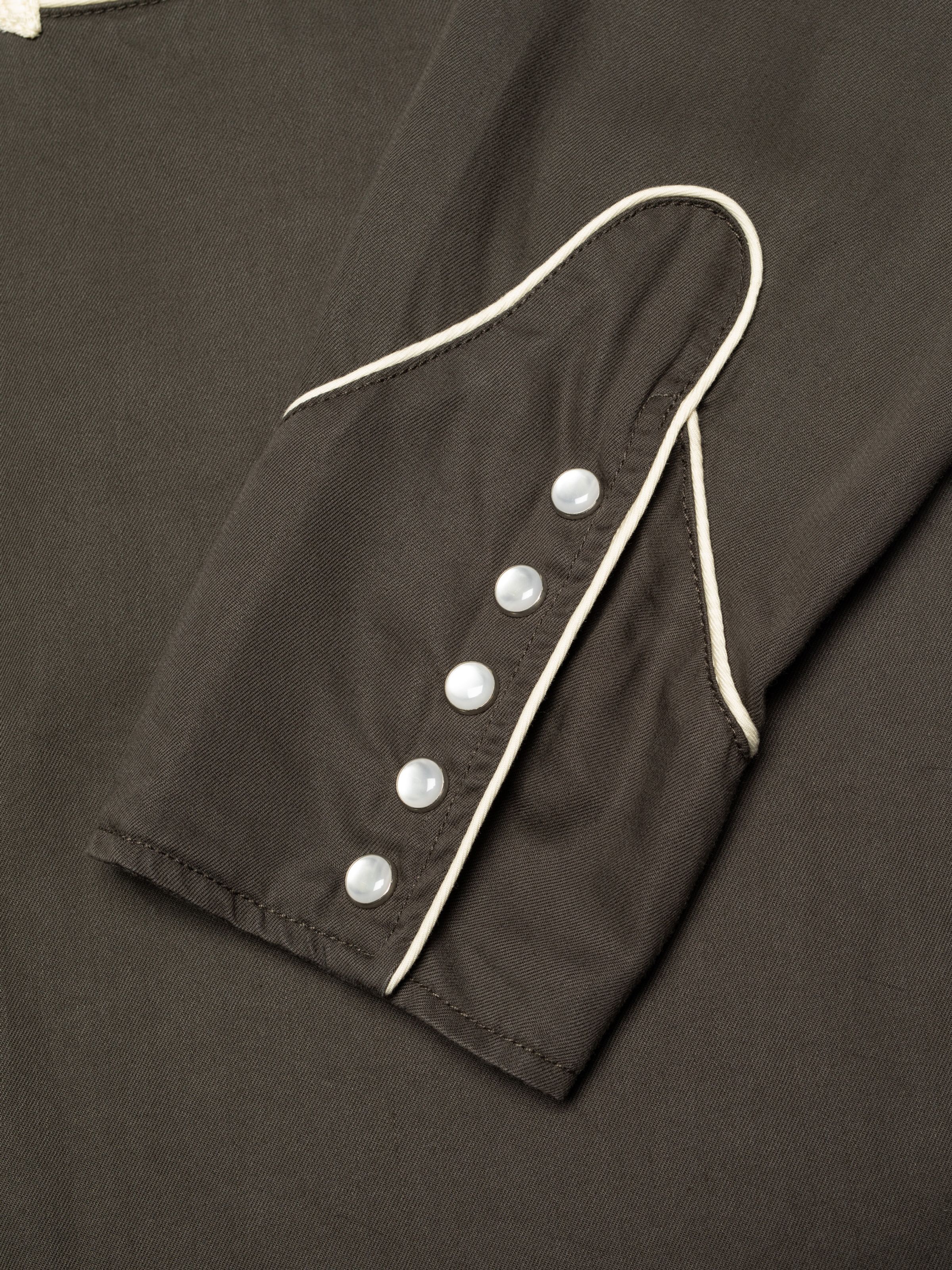 Nudie Jeans Gonzo Western Shirt Sunburns in black/brown, showing a close-up of the piped sleeve cuff with pearl snap buttons.