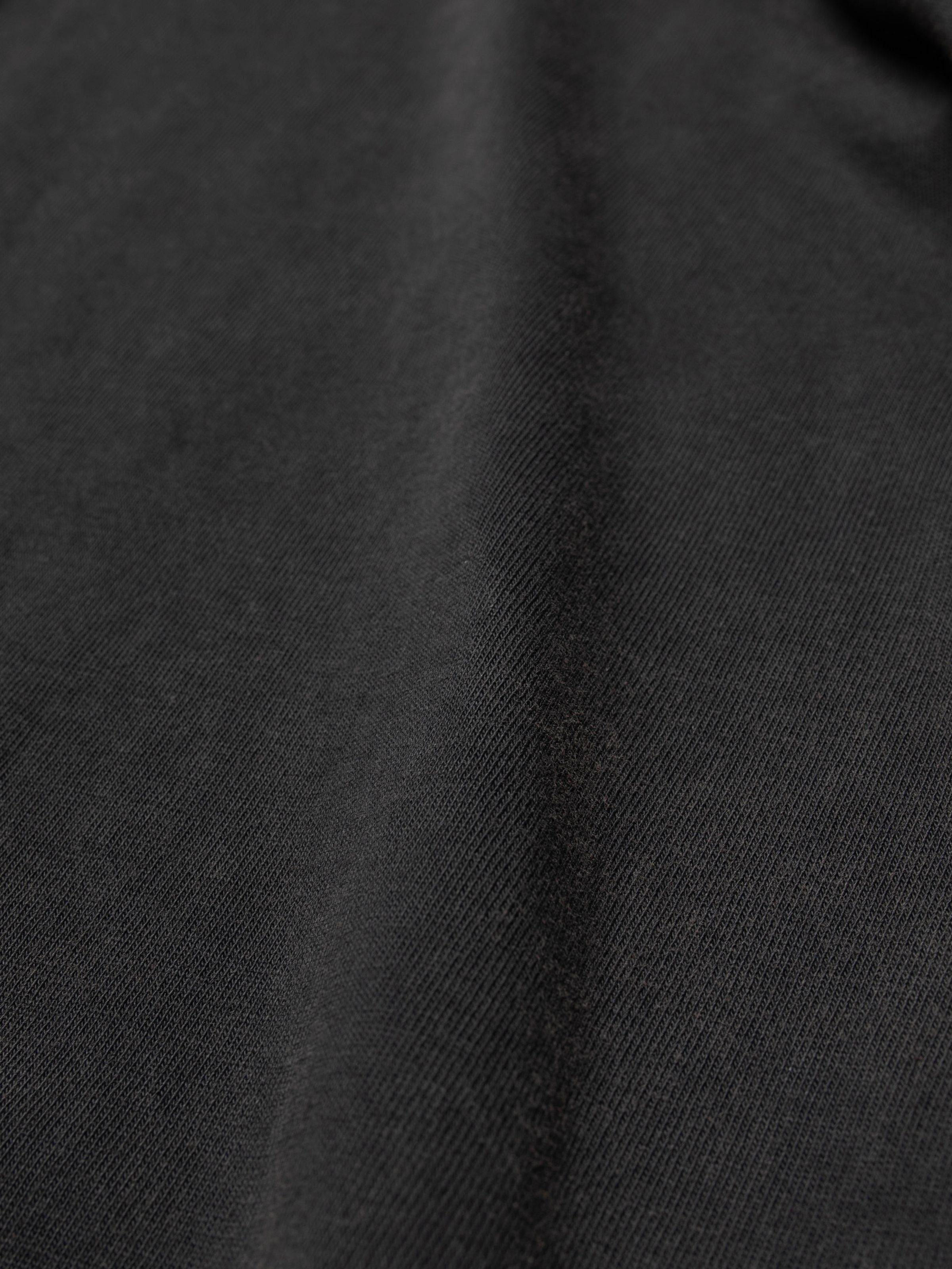 Nudie Jeans LS Henley Washed in Antracite, a close-up detail of the soft organic cotton jersey fabric texture.