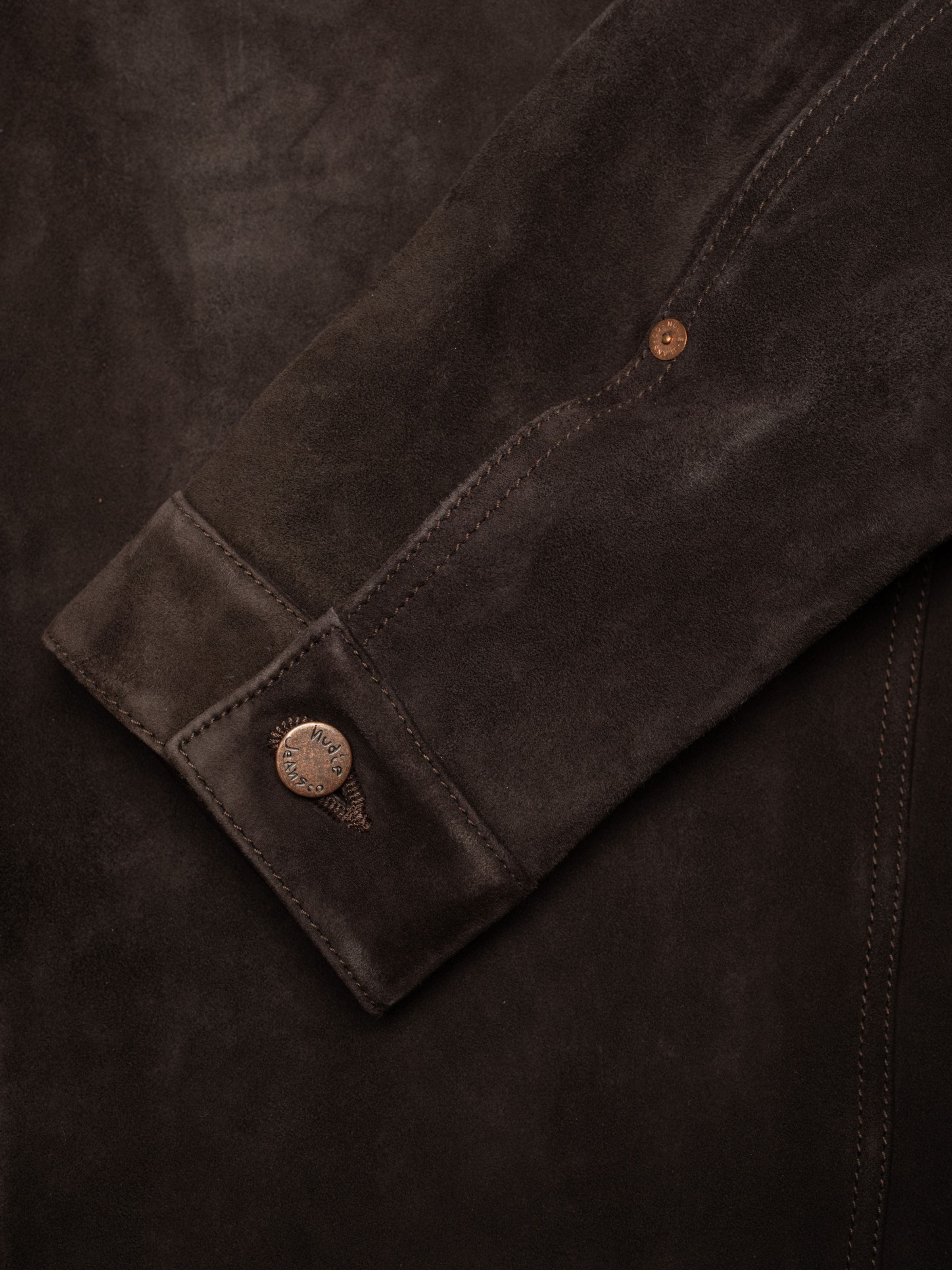 Nudie Jeans Dante II Suede Jacket in Dark Brown, a close-up of the sleeve showing the cuff and copper logo button.