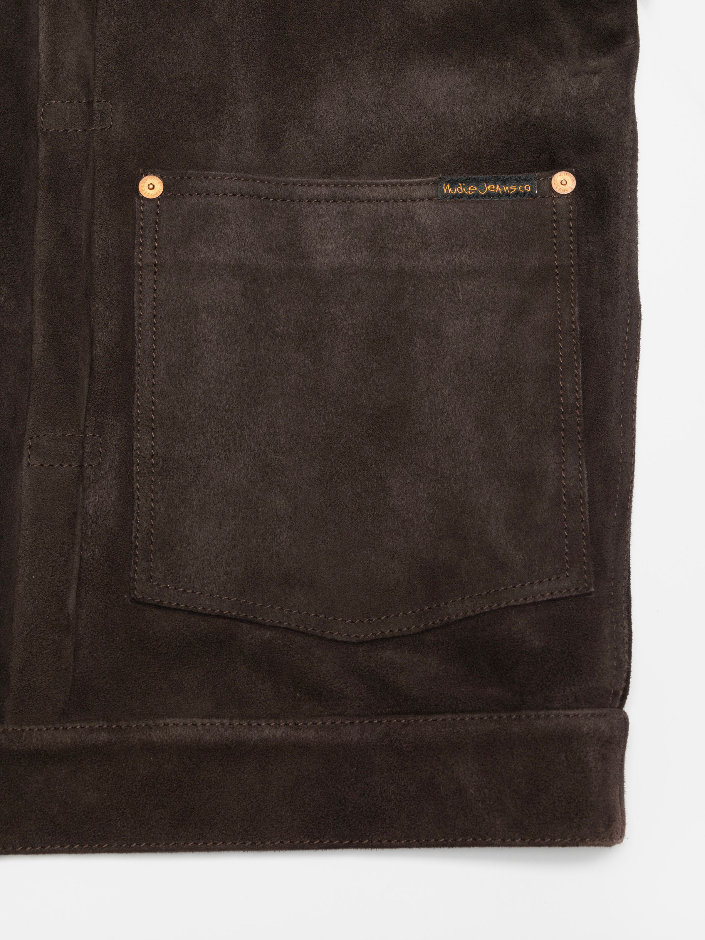 Nudie Jeans Dante II Suede Jacket in Dark Brown, close-up of a patch pocket showing the copper rivet and small logo label.