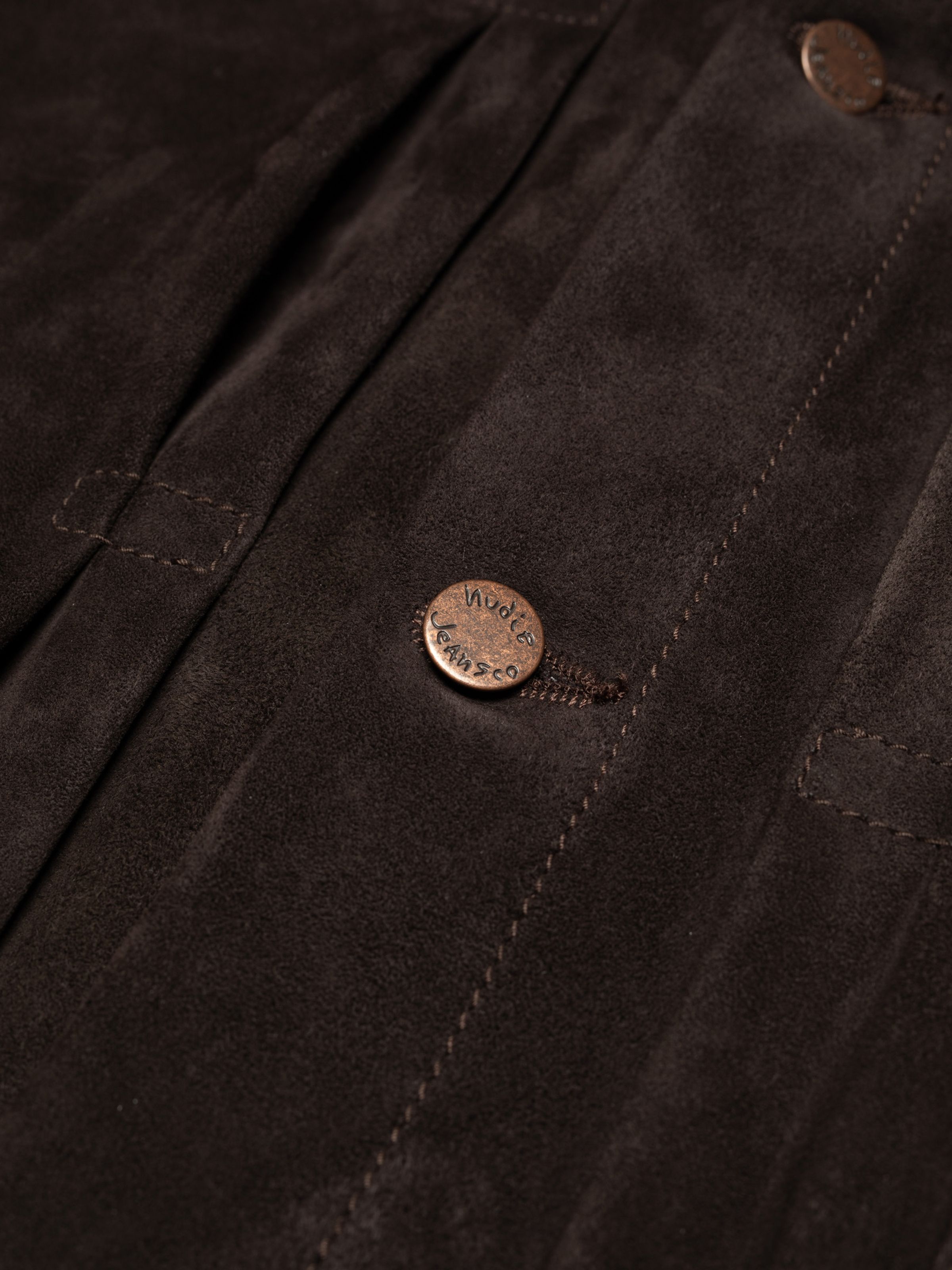 Nudie Jeans Dante II Suede Jacket in Dark Brown, a close-up of the men's pleated front and copper logo button.
