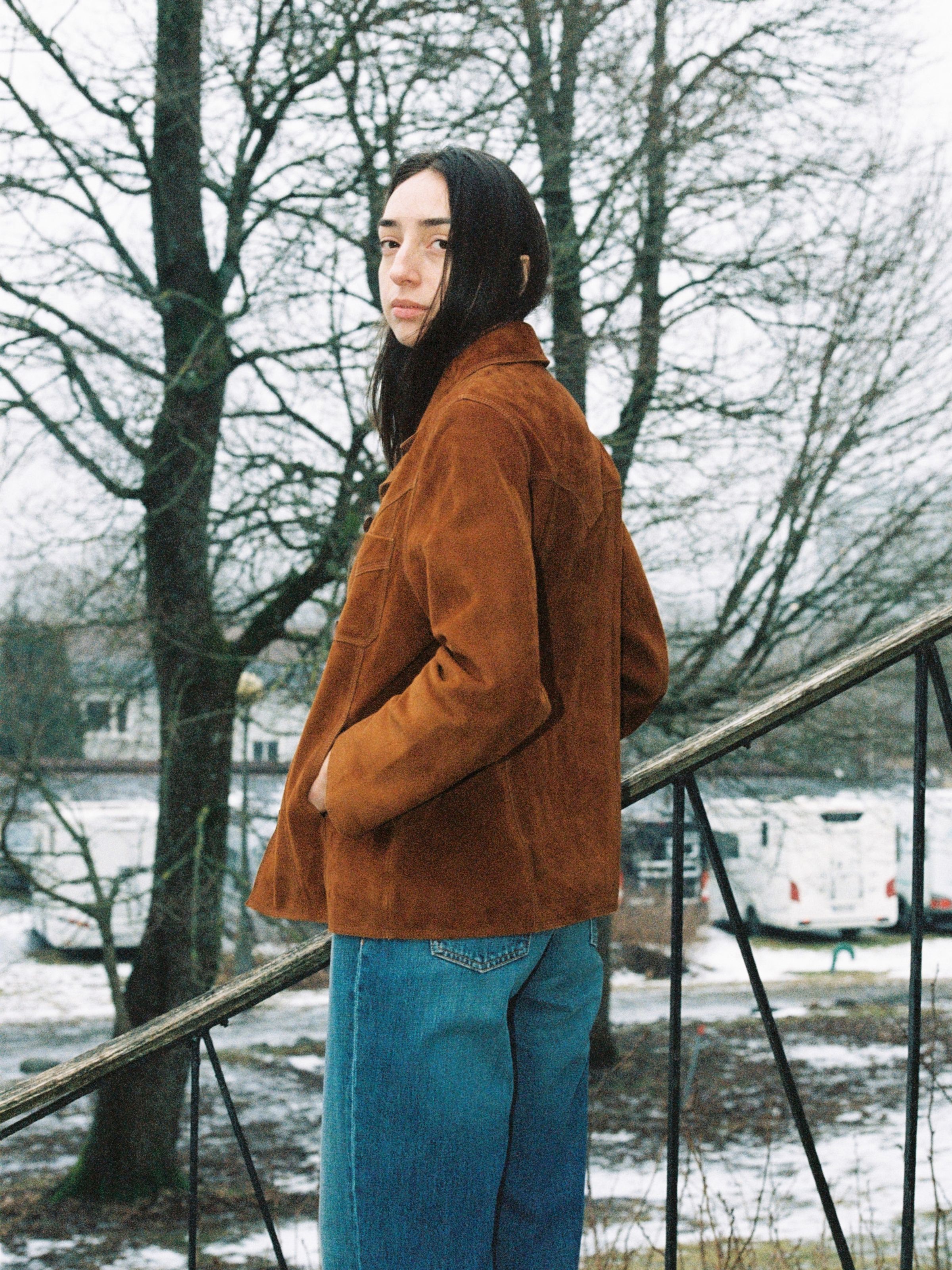 Nudie Jeans Peggy Suede Jacket in Cognac, a regular fit brown goat suede jacket worn by a woman in an outdoor setting.
