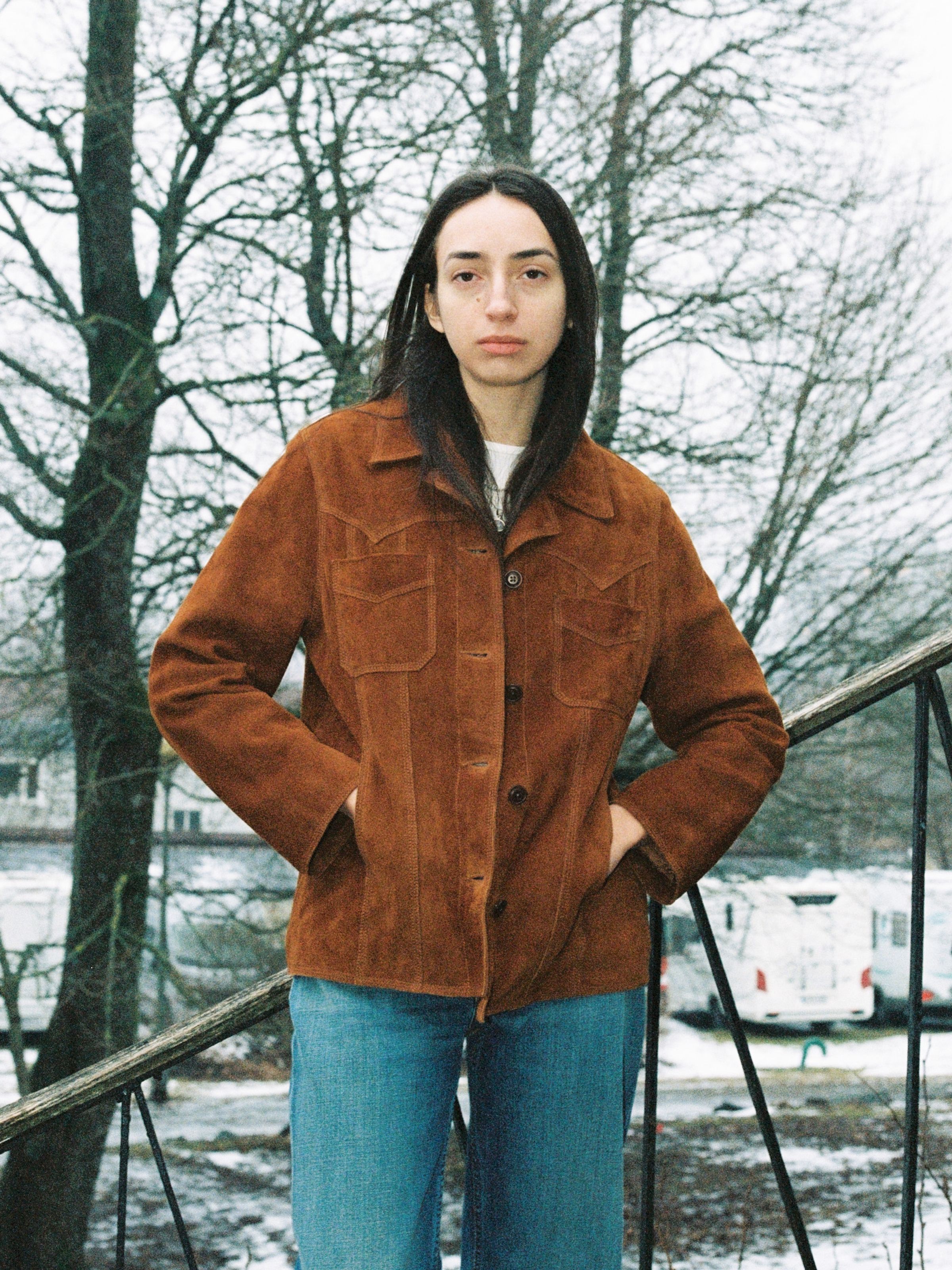Nudie Jeans Peggy Suede Jacket in Cognac, a women's goat leather jacket with pointed yokes shown on a model outdoors.