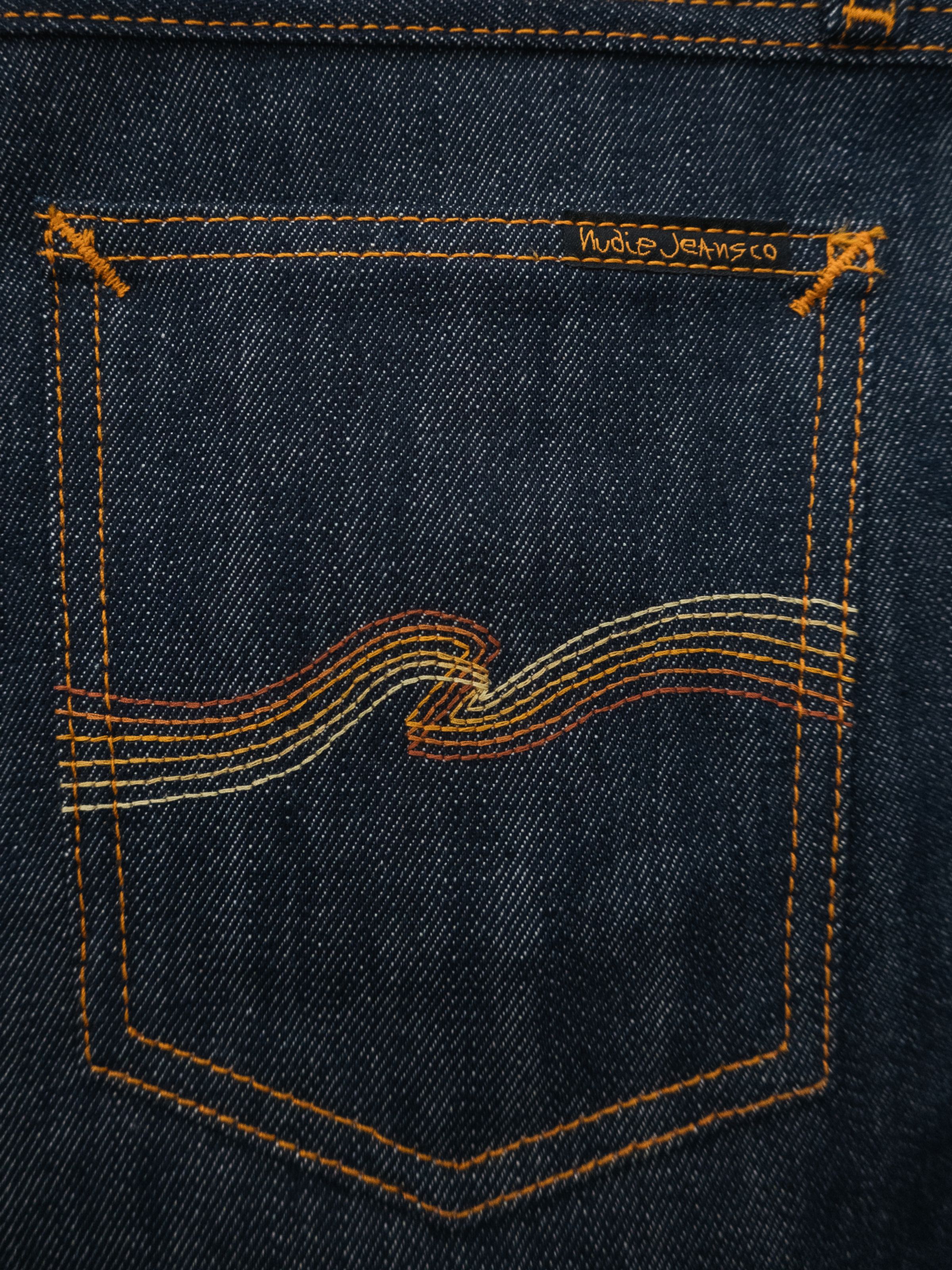 Nudie Jeans Tuff Tony Dry Sunburns, a close-up shot of the back pocket showing the signature sunburns gradient embroidery.