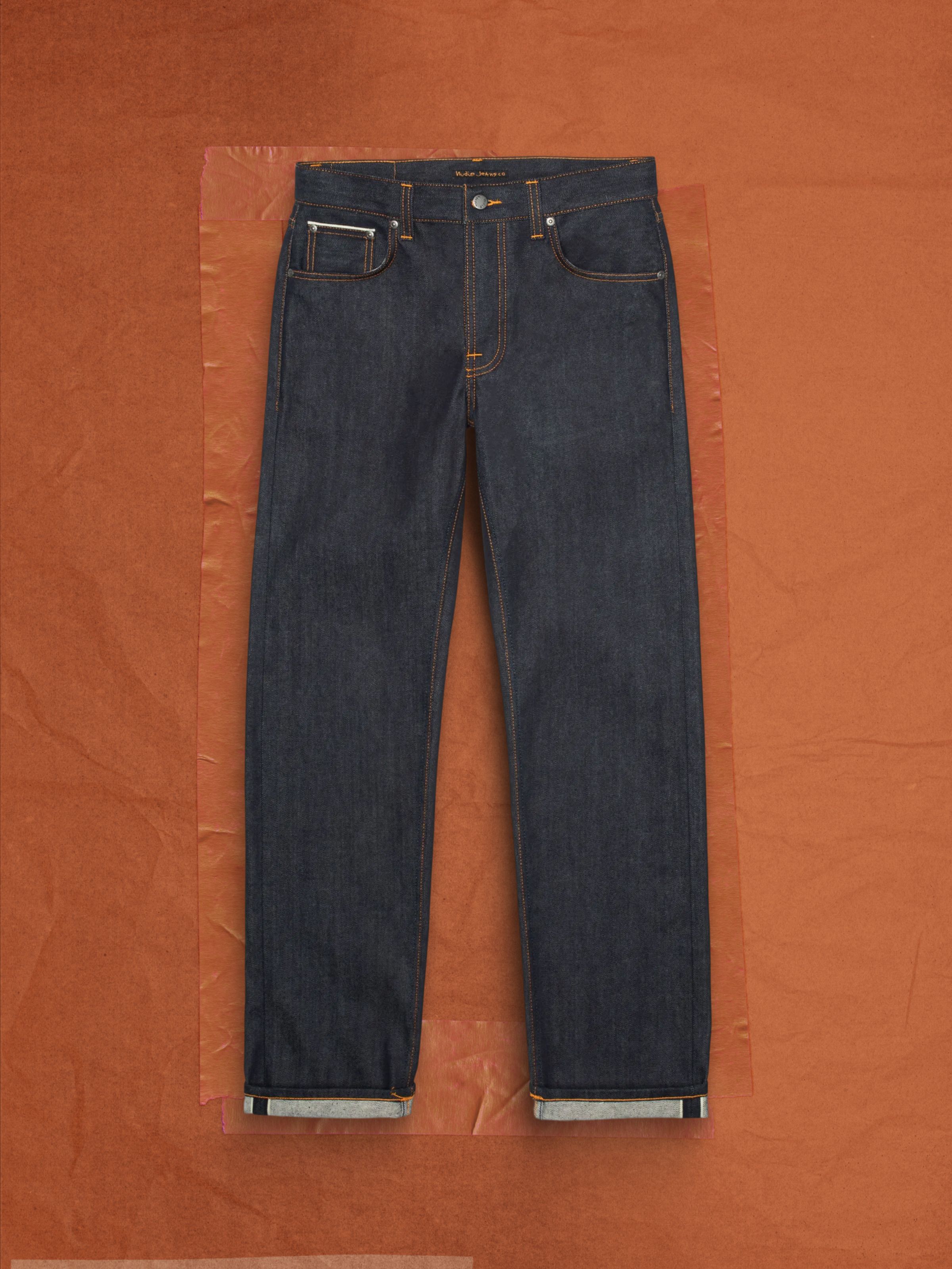 Nudie Jeans Rad Rufus Dry Dusk Selvage, men's regular fit straight leg jeans, laid flat on a brown background.