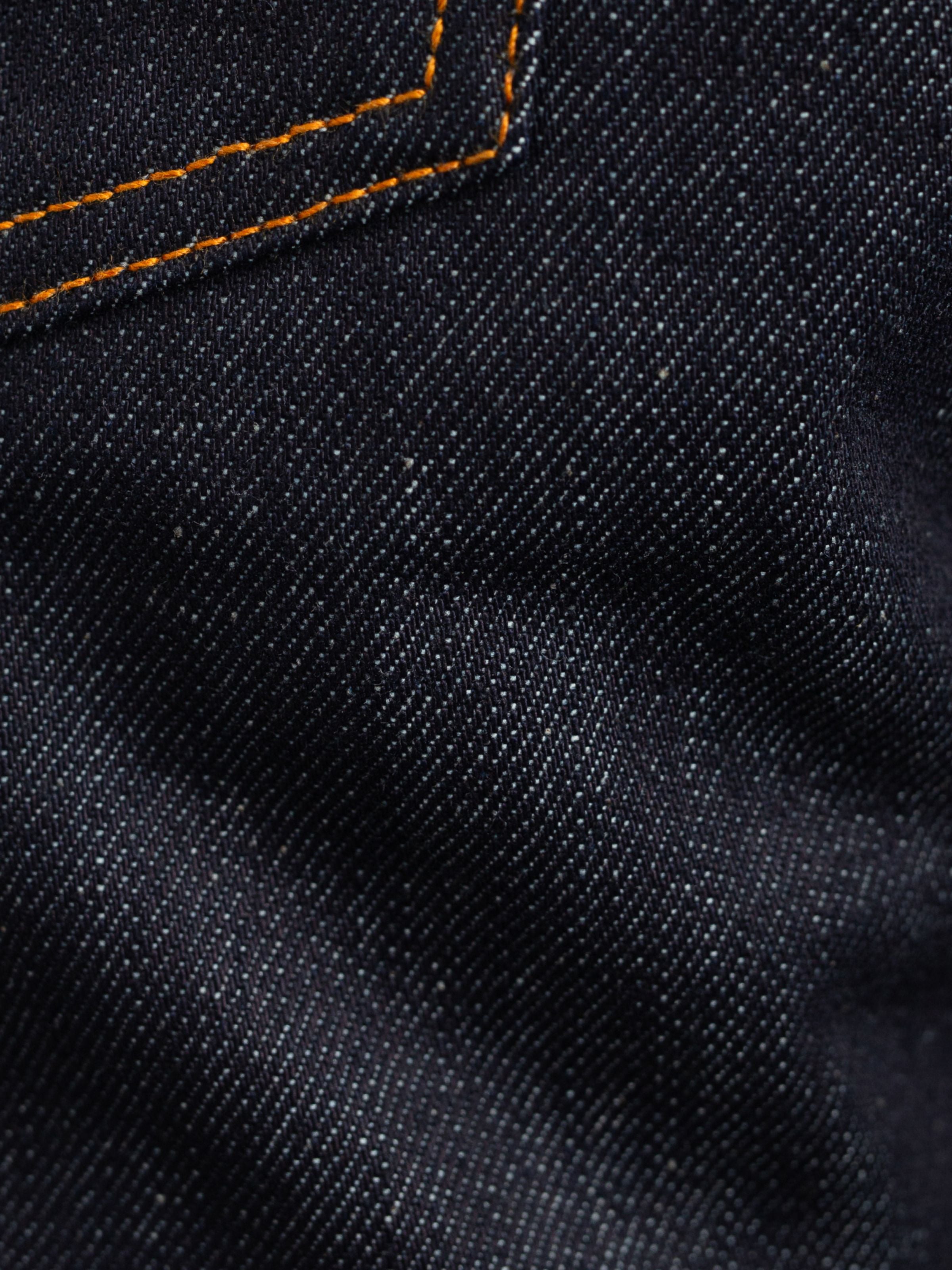 Nudie Jeans Rad Rufus Dry Dusk Selvage, Nahaufnahme der starren Selvedge-Denim-Textur und orangen Nähte.