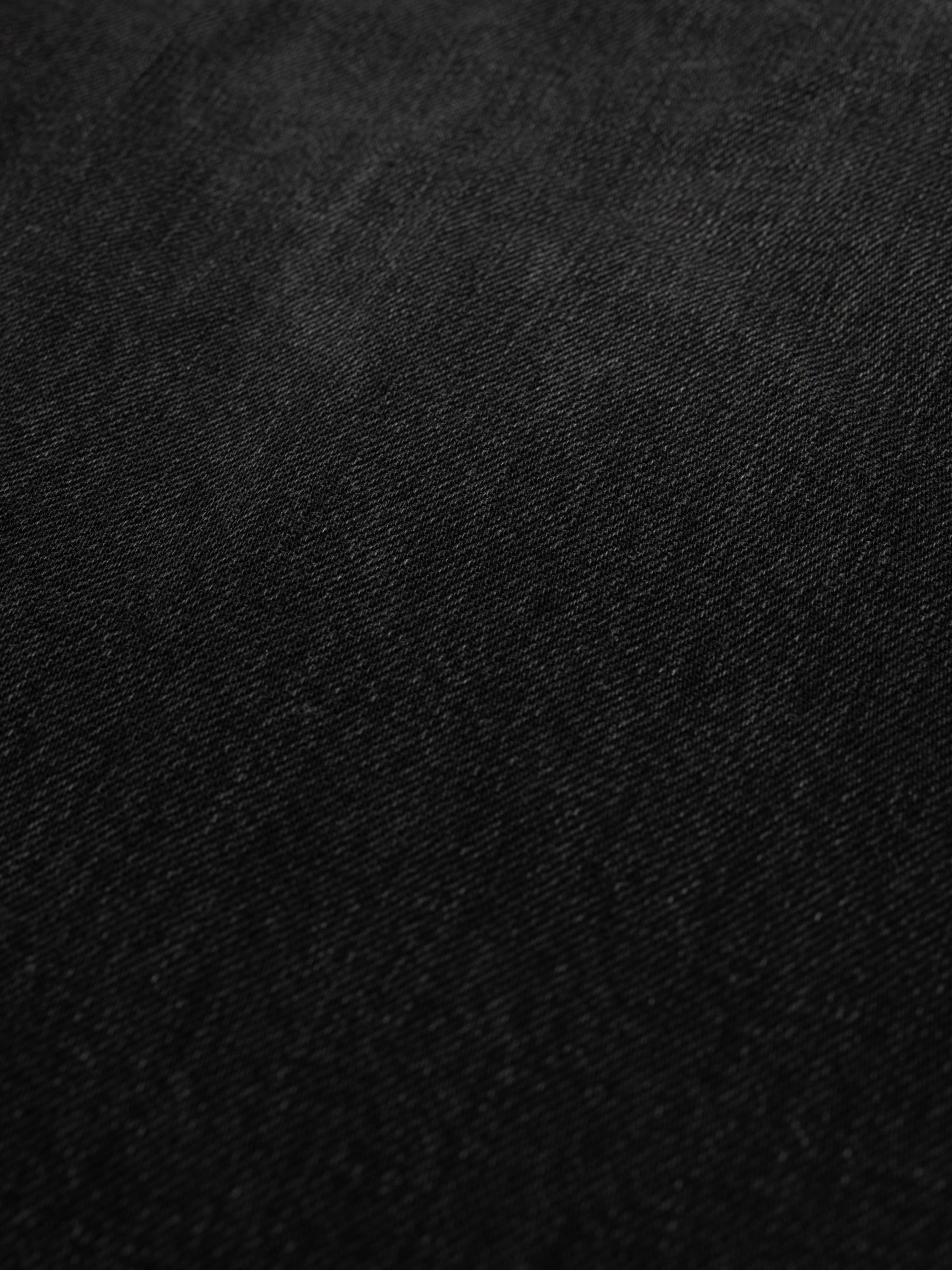 Nudie Jeans Loud Larry Black Storm, a pair of men's loose fit jeans in black denim, showing a close-up of the fabric texture.