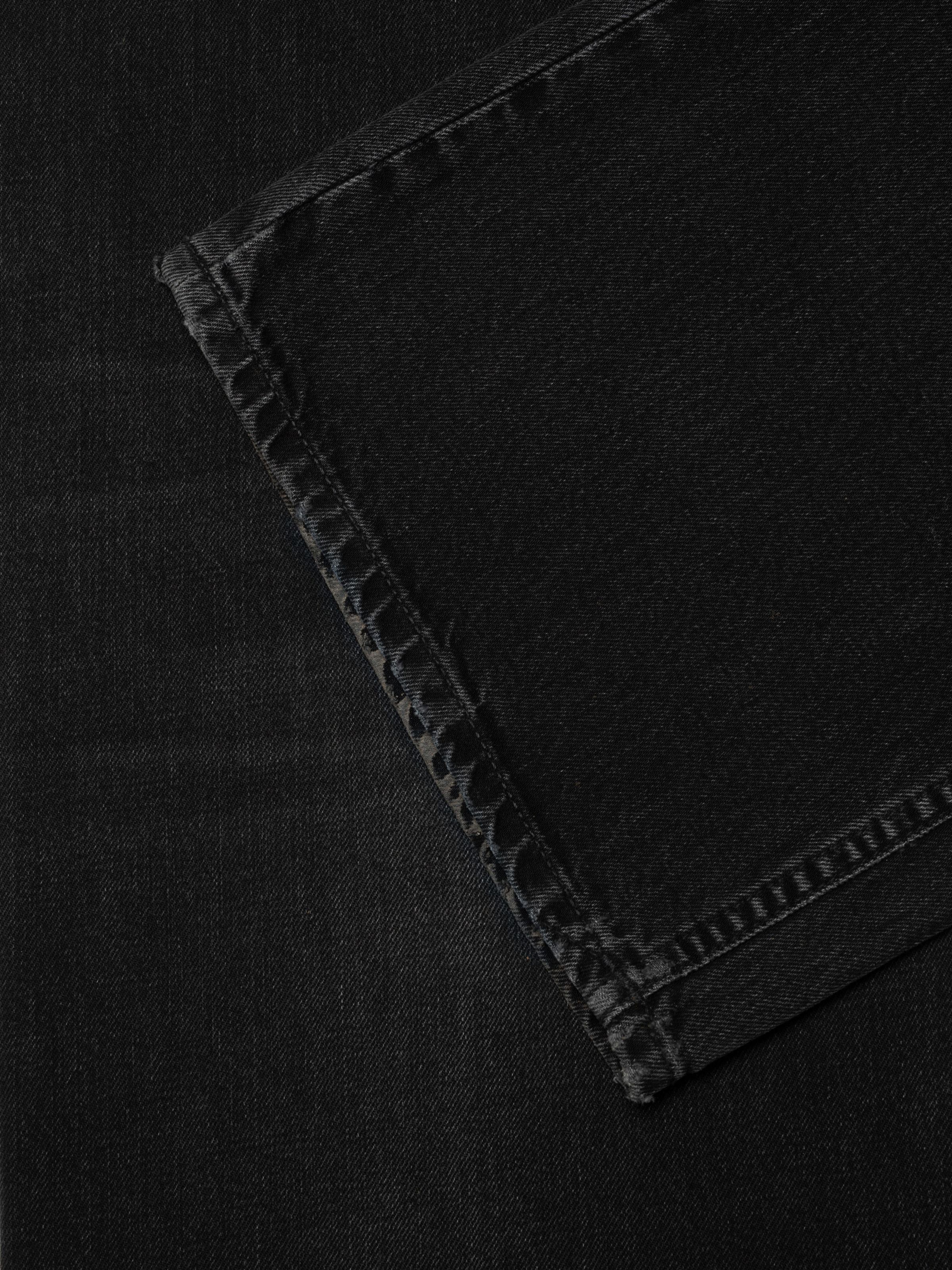 Nudie Jeans Loud Larry Black Storm, men's loose fit jeans in washed black denim, showing a detailed close-up of the hem.