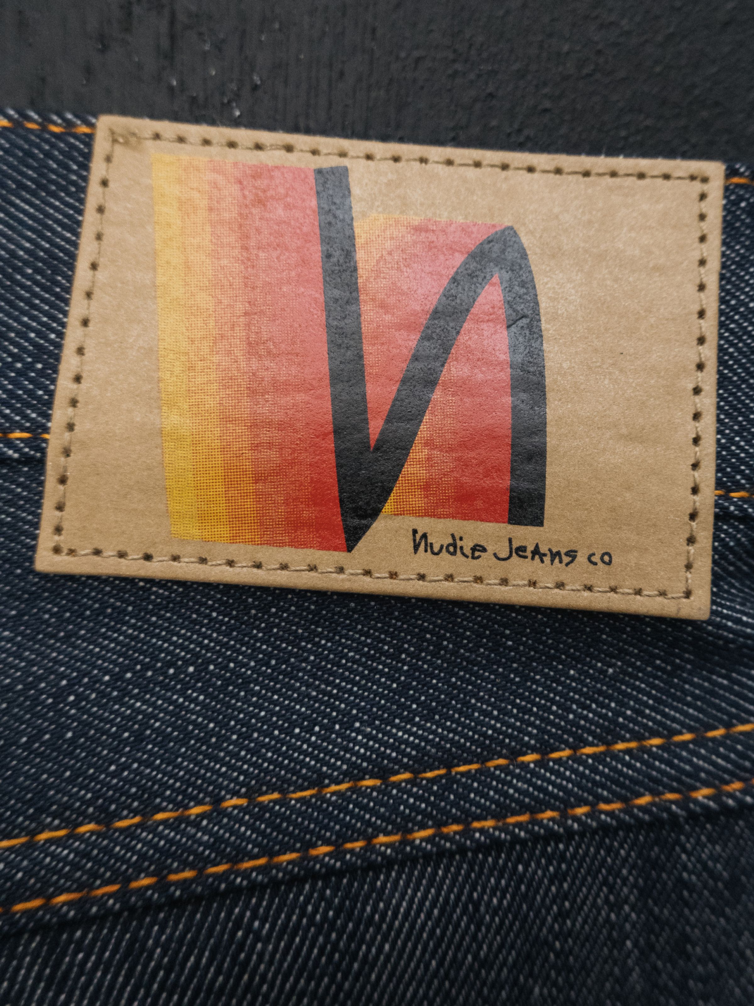 Nudie Jeans Lean Dean Dry Sunburns, a pair of men's slim fit jeans, showing a close-up of the sunburns gradient Jacron patch.