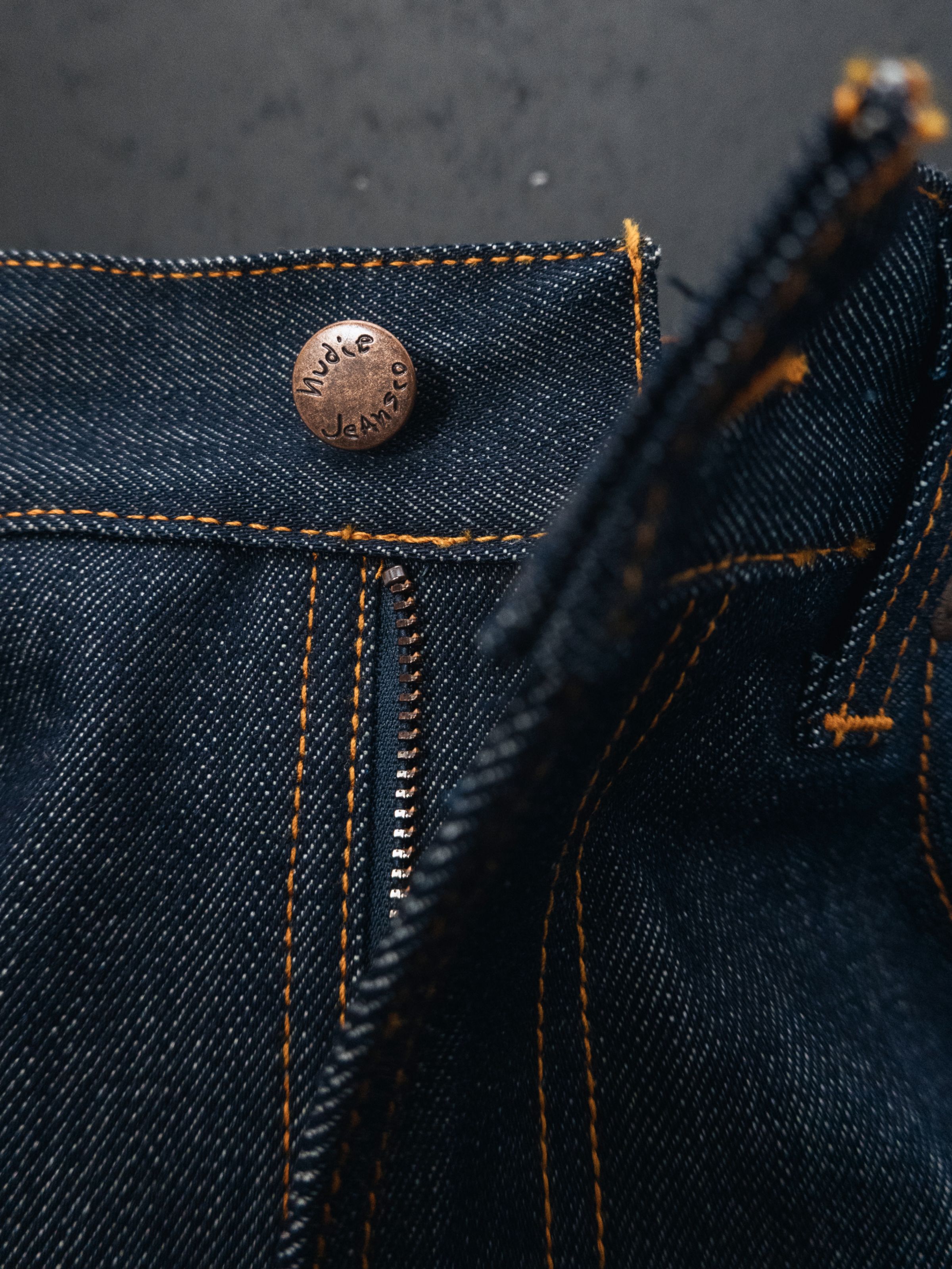 Nudie Jeans Lean Dean Dry Sunburns, men's slim tapered jeans in dry blue denim, showing the copper button and zip fly.