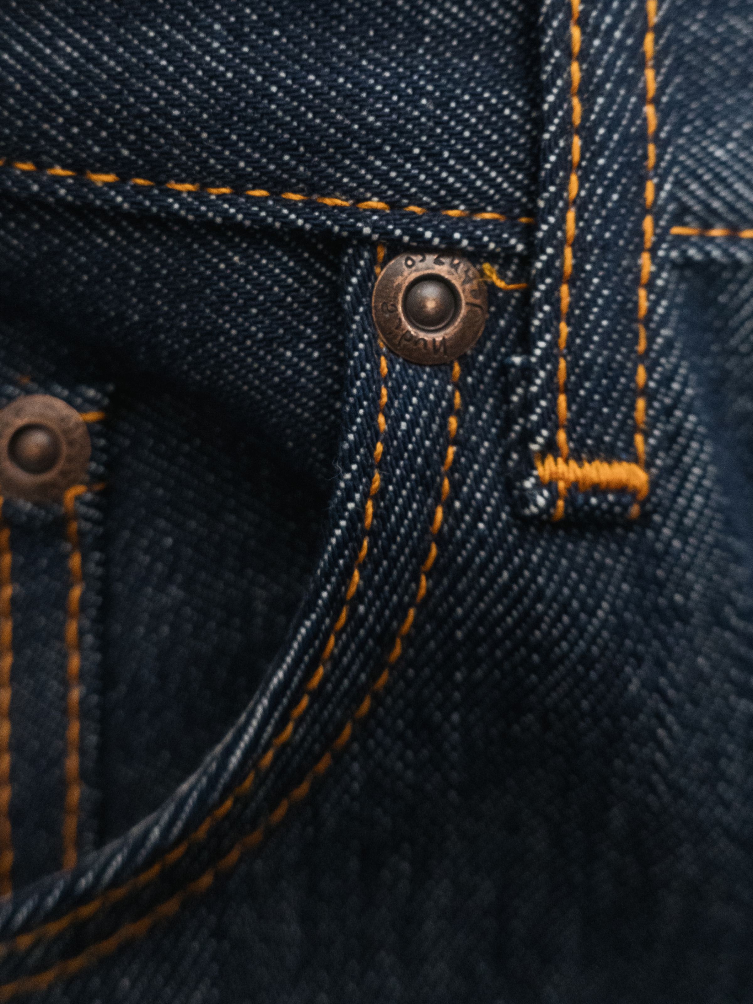 Nudie Jeans Lean Dean Dry Sunburns, a men's jean in dry blue denim, shown in a close-up of the front pocket and copper rivet.